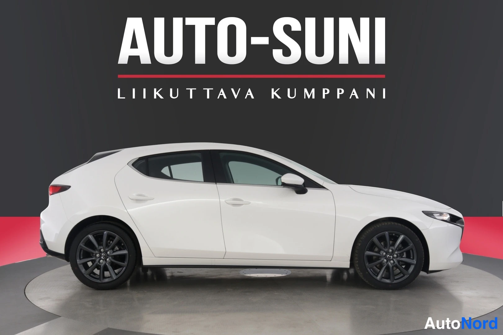 Sivulta: Valkoisen Mazda 3 -viistoperän sivukuva oikealta päin, tummat kevytmetallivanteet.