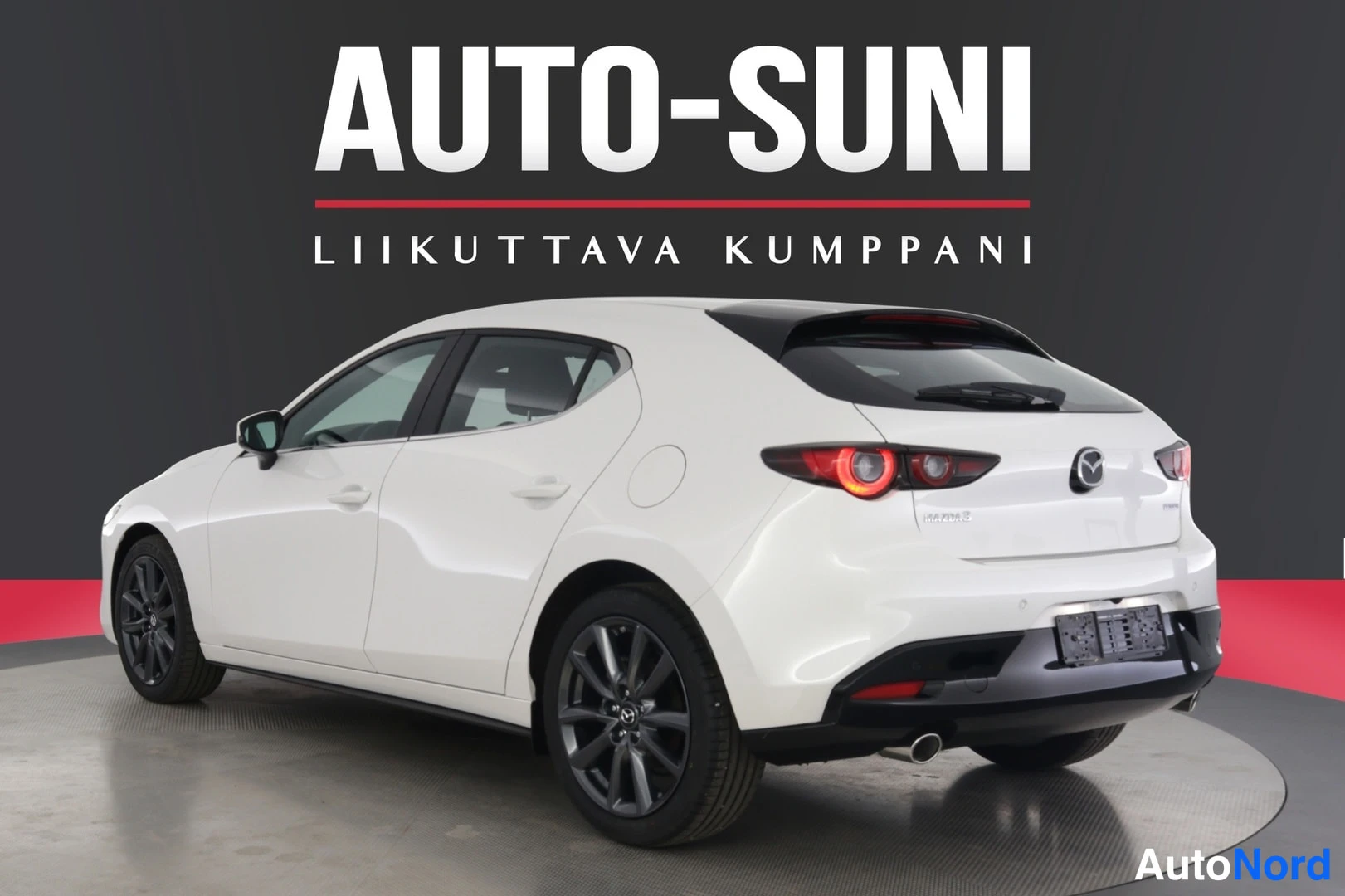 Takaviisto: Valkoinen Mazda 3 takaviistolta oikealle, musta takaovessa kuvattu katto ja tummat vanteet.