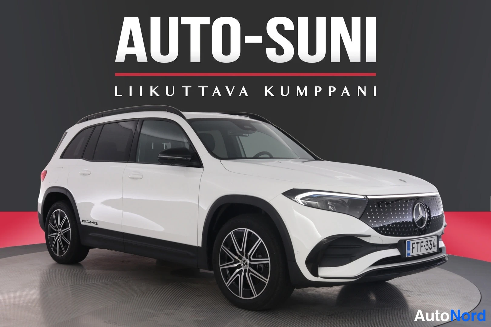 Etuviisto, nokka oikealle: Valkoinen Mercedes-Benz EQB kuvattu kolmannelta etukulmalta, kevytmetallivanteet ja kattokaiteet näkyvissä.