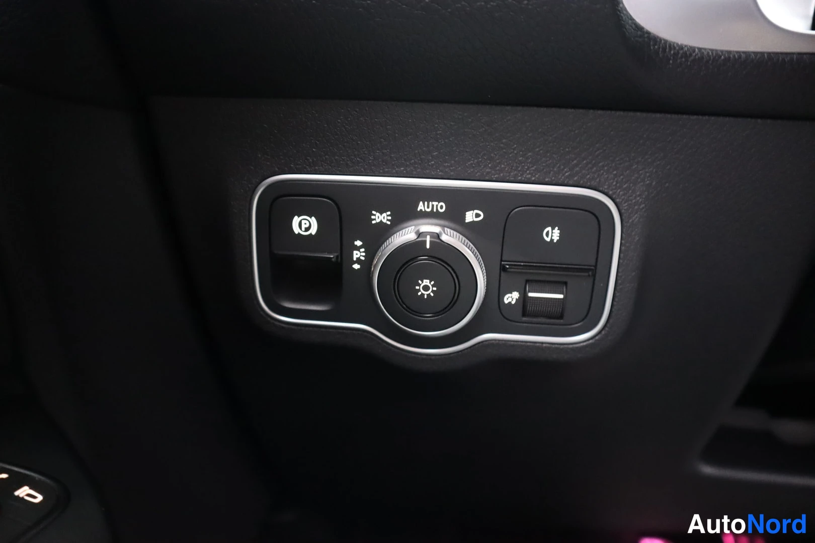 Yksityiskohta: Kojeiston valokatkaisinryhmä AUTO-merkillä, parkkitutkan p-nappi, sumuvalojen säädöt ja lukitukset.