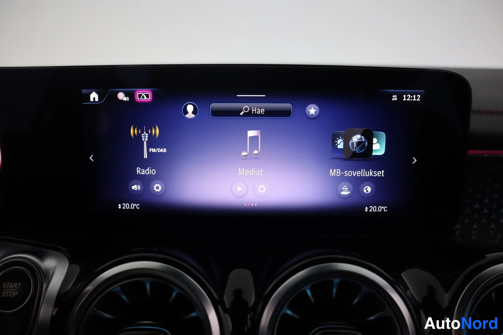 Yksityiskohta: Mercedes-Benzin kosketusnäyttö näyttää radio-, mediat- ja MB-sovellukset-valikot sekä lämpötilan 20.0°C ja kellonajan 12:12.