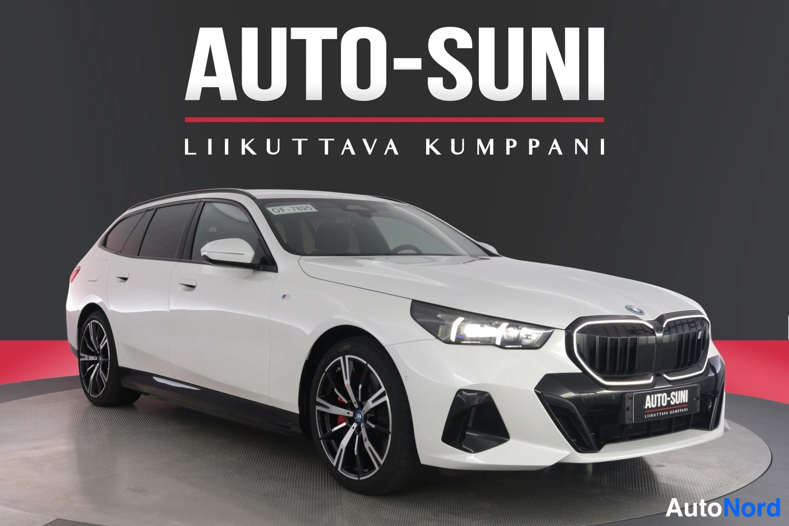 Etuviisto, nokka oikealle: Valkoinen farmarimallinen henkilöauto studiomaisessa kuvassa, etukulmasta oikealta vasemmalle; musta säleikkö ja LED-ajovalot, tummat kevytmetallivanteet