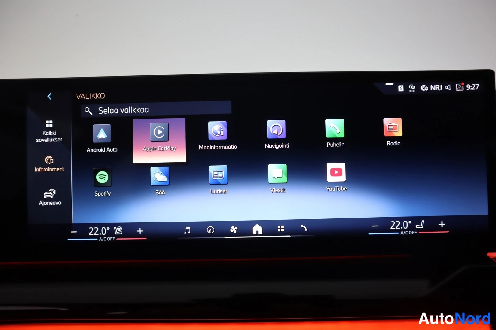 Edestä: Auton infotainment-näytön valikko sovelluskuvakkeineen, muun muassa Apple CarPlay, Android Auto, Spotify ja navigointi.