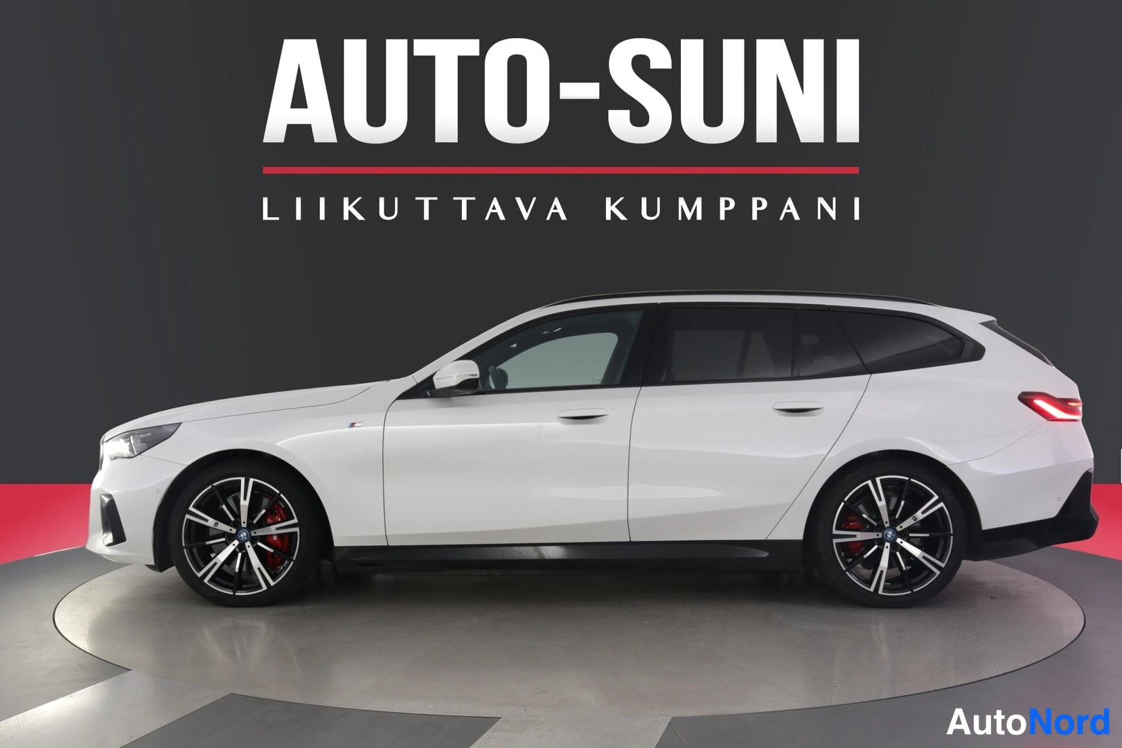Sivulta: Valkoinen farmariauto kuvattu sivulta, keula vasemmalla, studio- tai esittelytaustassa.