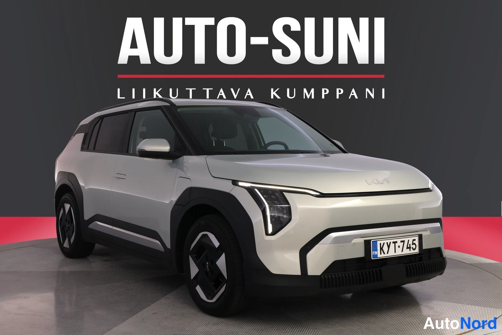Etuviisto, nokka oikealle: Valkoinen Kia EV3 esitään kolmenespesäkuvassa etunosa oikealla, tummaa studioympäristöä vasten, rekisterikilpi.