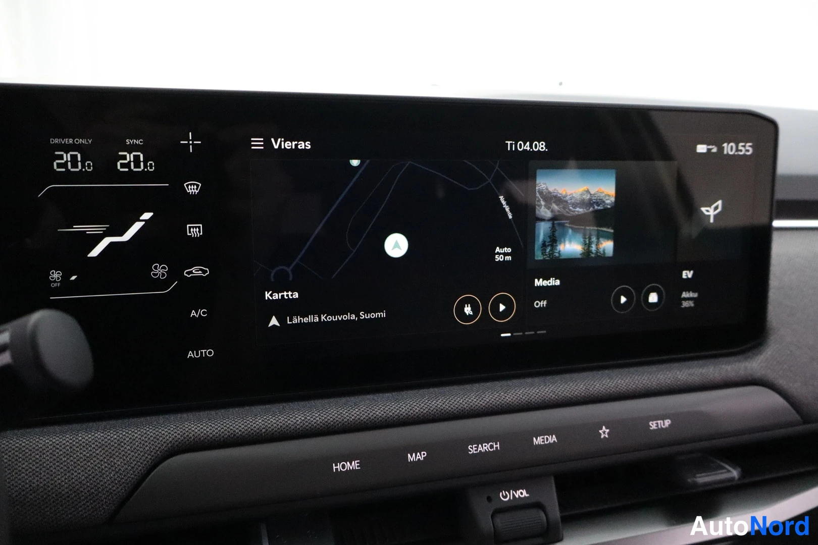 Sivulta: Kuvassa auton kojelaudan infotainment-näyttö ja digitaalinen mittaristo. Näytössä on karttanäkymä tekstillä 'Kartta' ja 'Lähellä Kouvola, Suomi', sekä media- ja