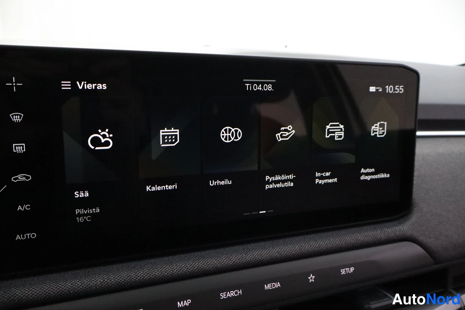 Sivulta: Kuvassa auton infotainment-näytön sovellusvalikon toinen sivu, jossa ovat kuvakkeet 'Sää' (Pilvistä 16°C), 'Kalenteri', 'Urheilu', 'Pysäköinti-palvelutila', 'In