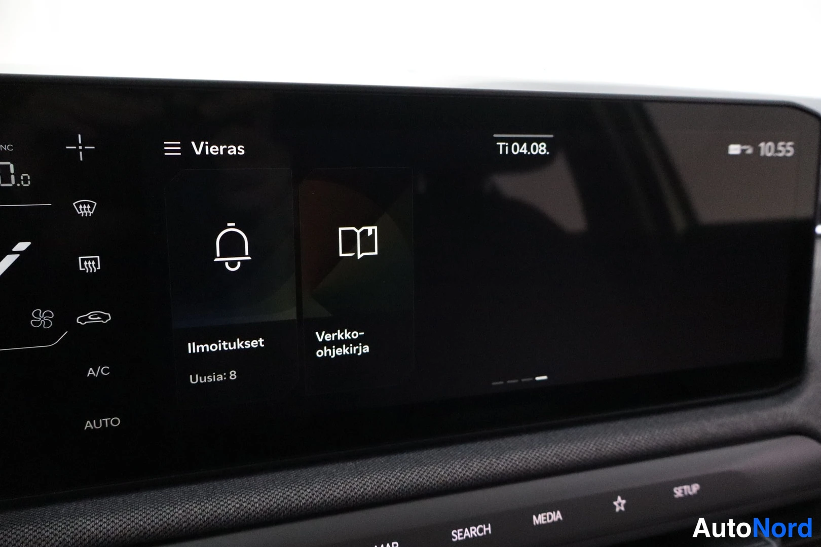 Yksityiskohta: Infotainment-näytön lähikuva, jossa näkyy Vieras-profiili, Ilmoitukset (Uusia: 8), Verkko-ohjekirja, kellonaika 10.55 ja fyysiset painikkeet SEARCH, MEDIA ja SE