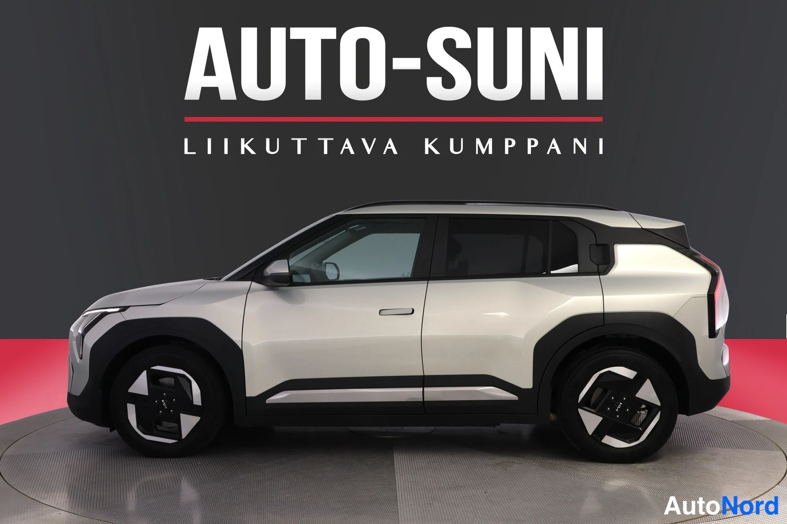 Sivulta: Kia EV3:n sivukuva, hopeanharmaa koripaneelit ja mustat pyöränkaaret, taustalla Auto-Suni-logo.