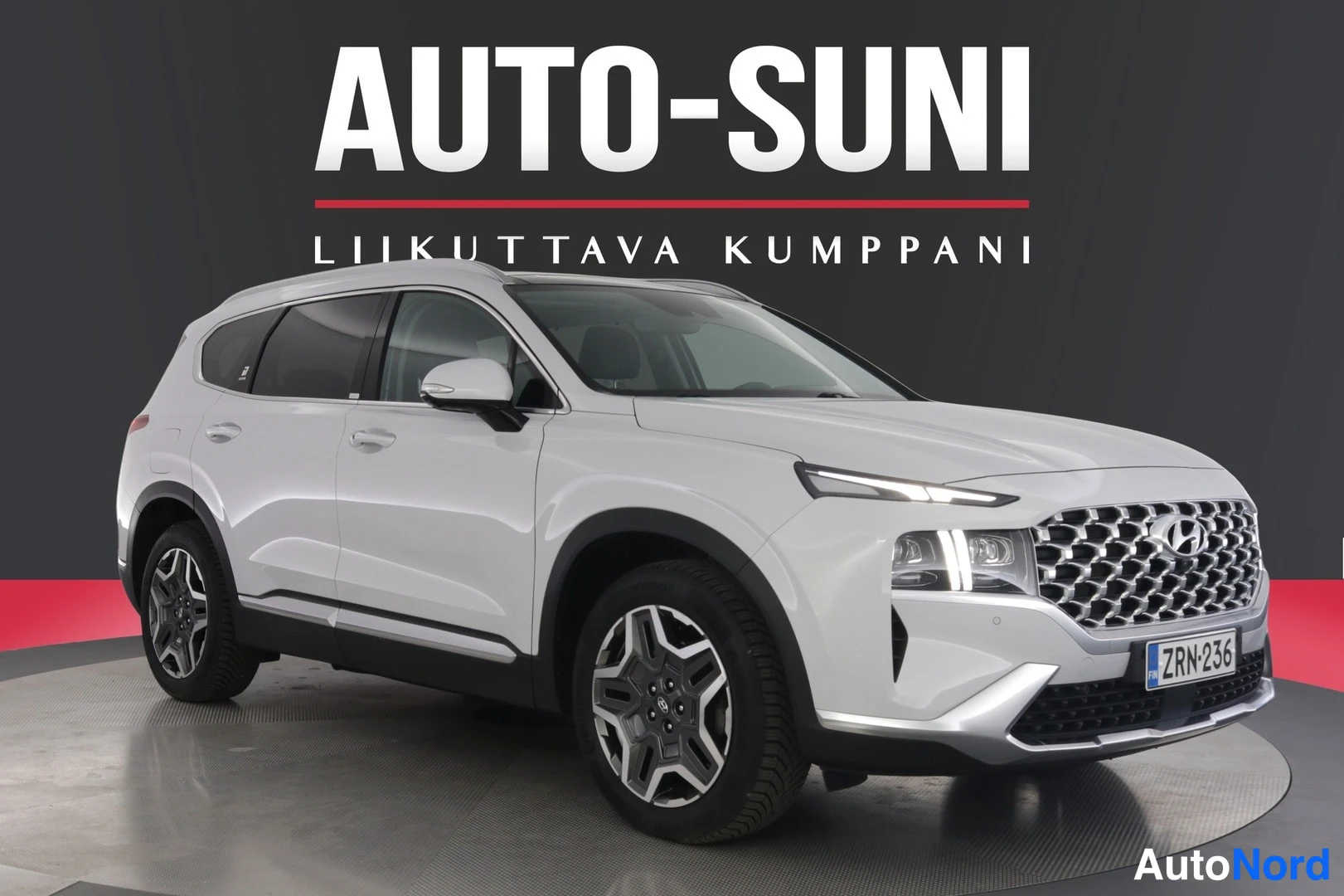 Etuviisto, nokka oikealle: Hyundai Santa Fe -maasturi edestä oikealta sivulta kuvattuna, valkoinen, rekisterikilpi.