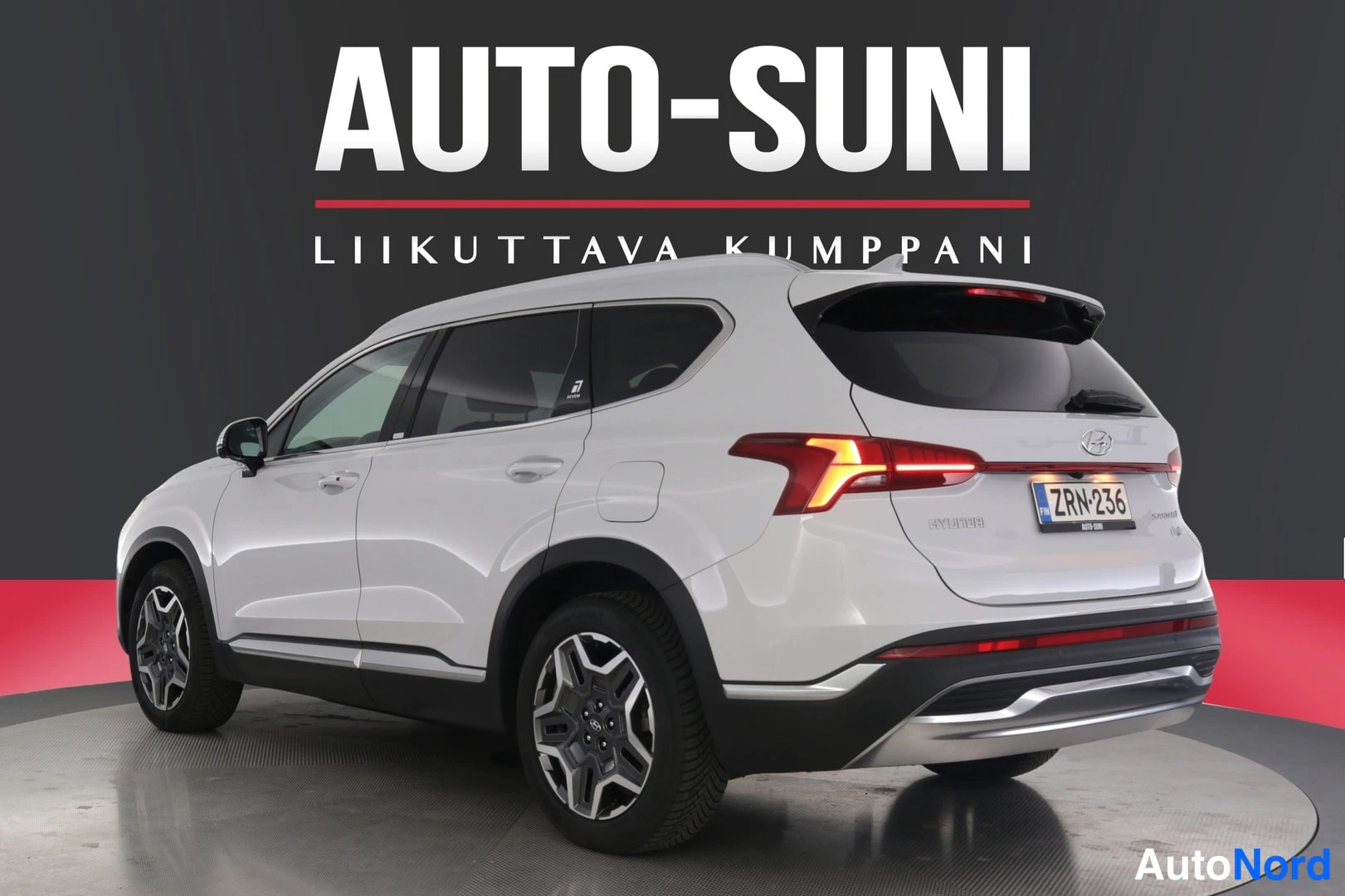 Takaviisto: Hyundai Santa Fe -maasturi takaa vasemmalta sivulta kuvattuna, valkoinen, takavalot syttyvät, rekisterikilpi.