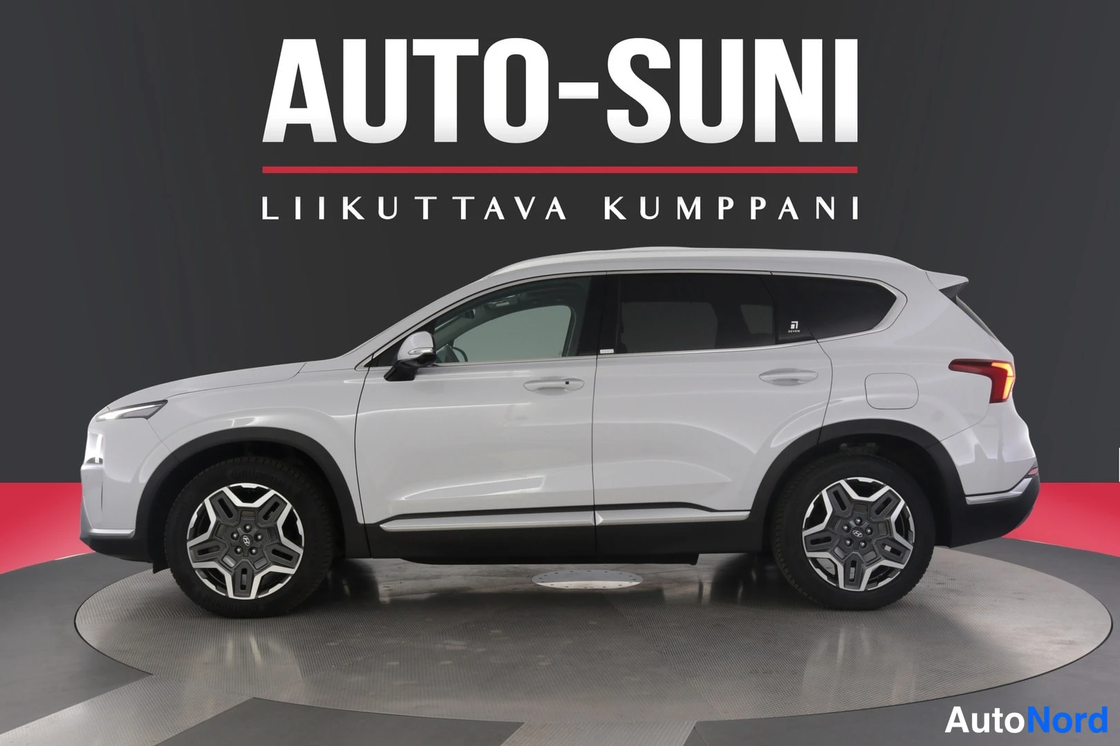 Sivulta: Valkoinen Hyundai Santa Fe -maasturin sivukuva studiotaustaa vasten, AUTO-SUNI-logolla.