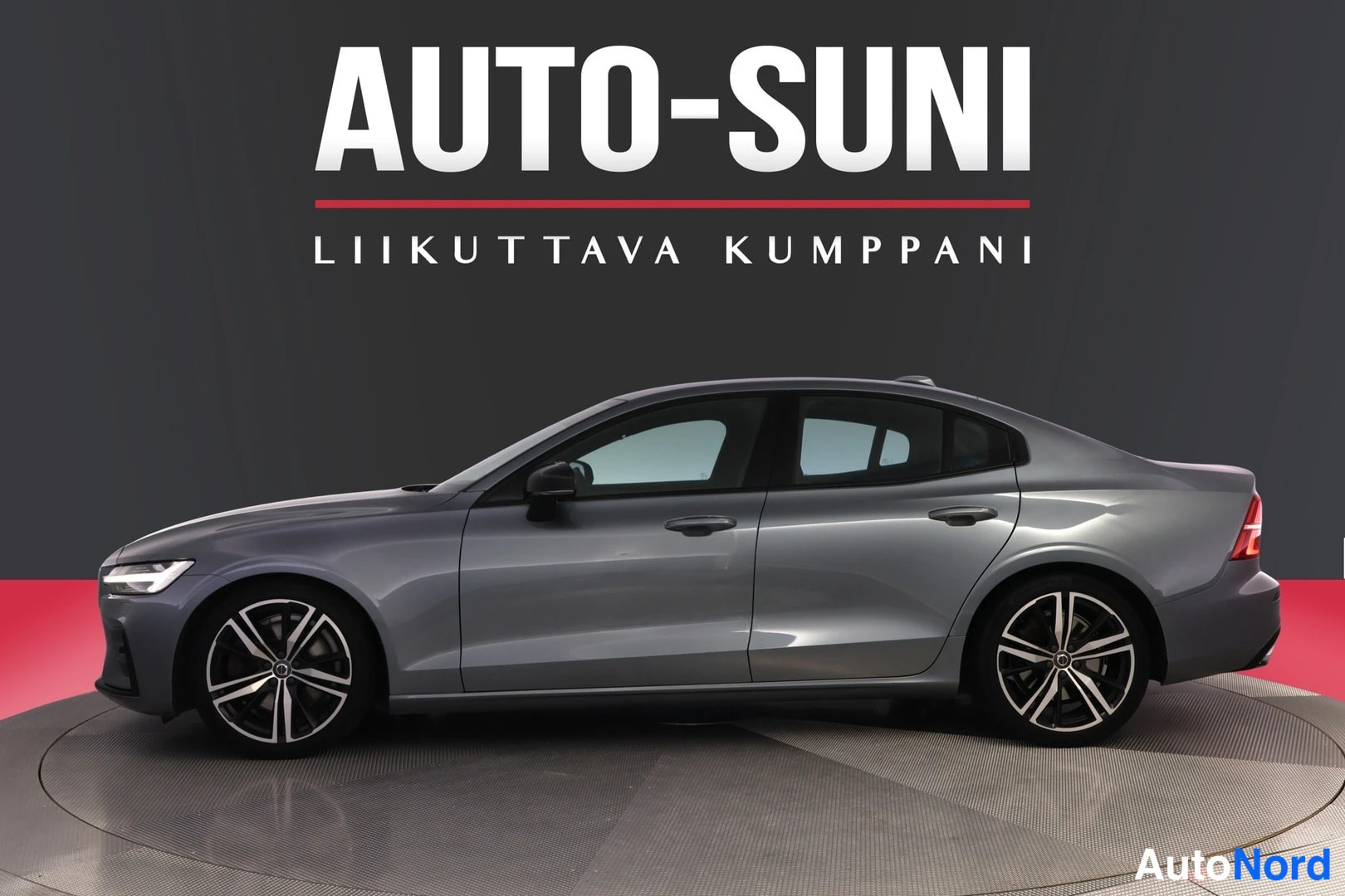 Sivulta: Auton etukulma vasemmalta, tummanharmaa sedan, studio, taustalla AUTO-SUNI-logo