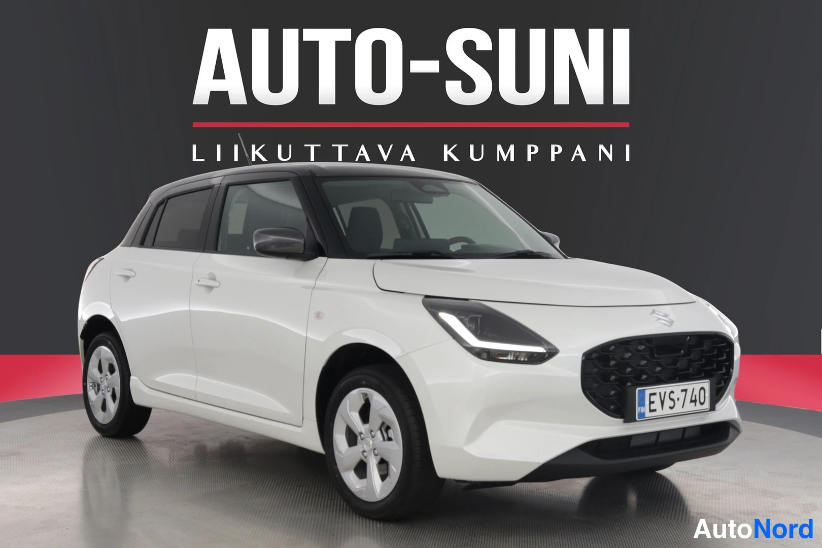Etuviisto, nokka oikealle: Valkoinen Suzuki Swift etukolmannelta oikealta, rekisteritunnus, musta katto, studio-tausta.
