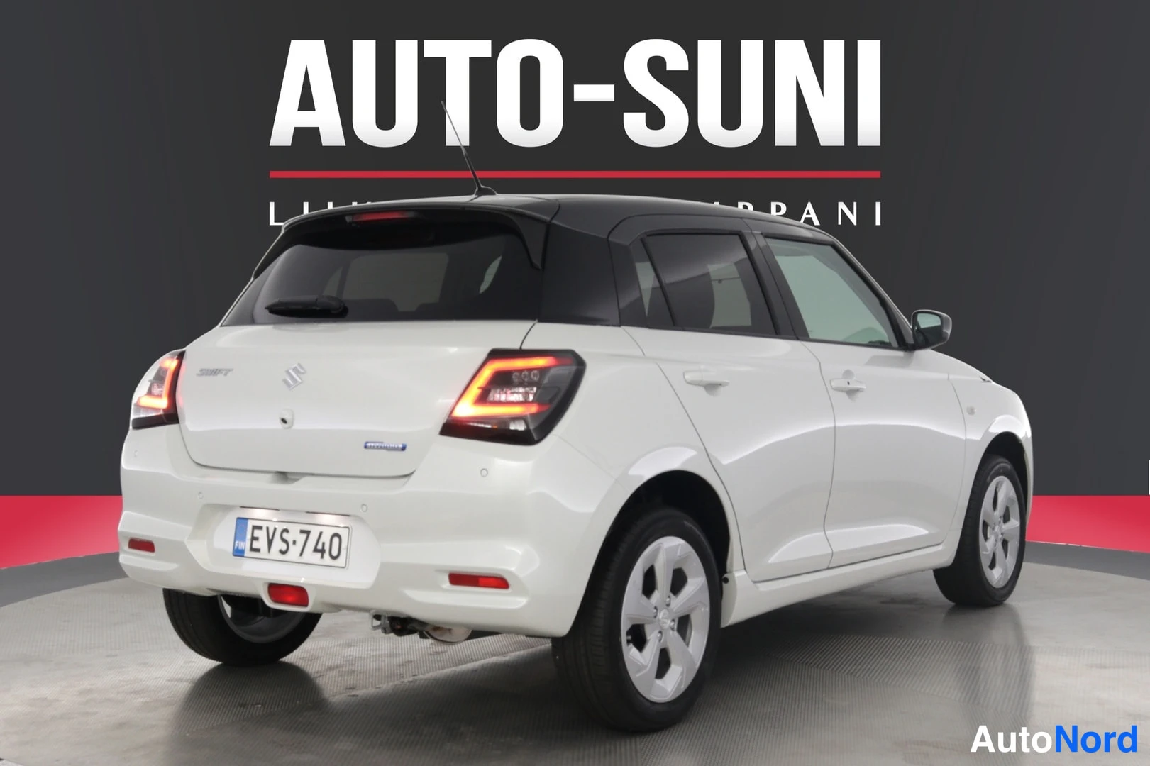 Takaviisto: Valkoinen Suzuki Swift takakolmannelta vasemmalta, rekisteritunnus, musta katto, takavalot palamassa.