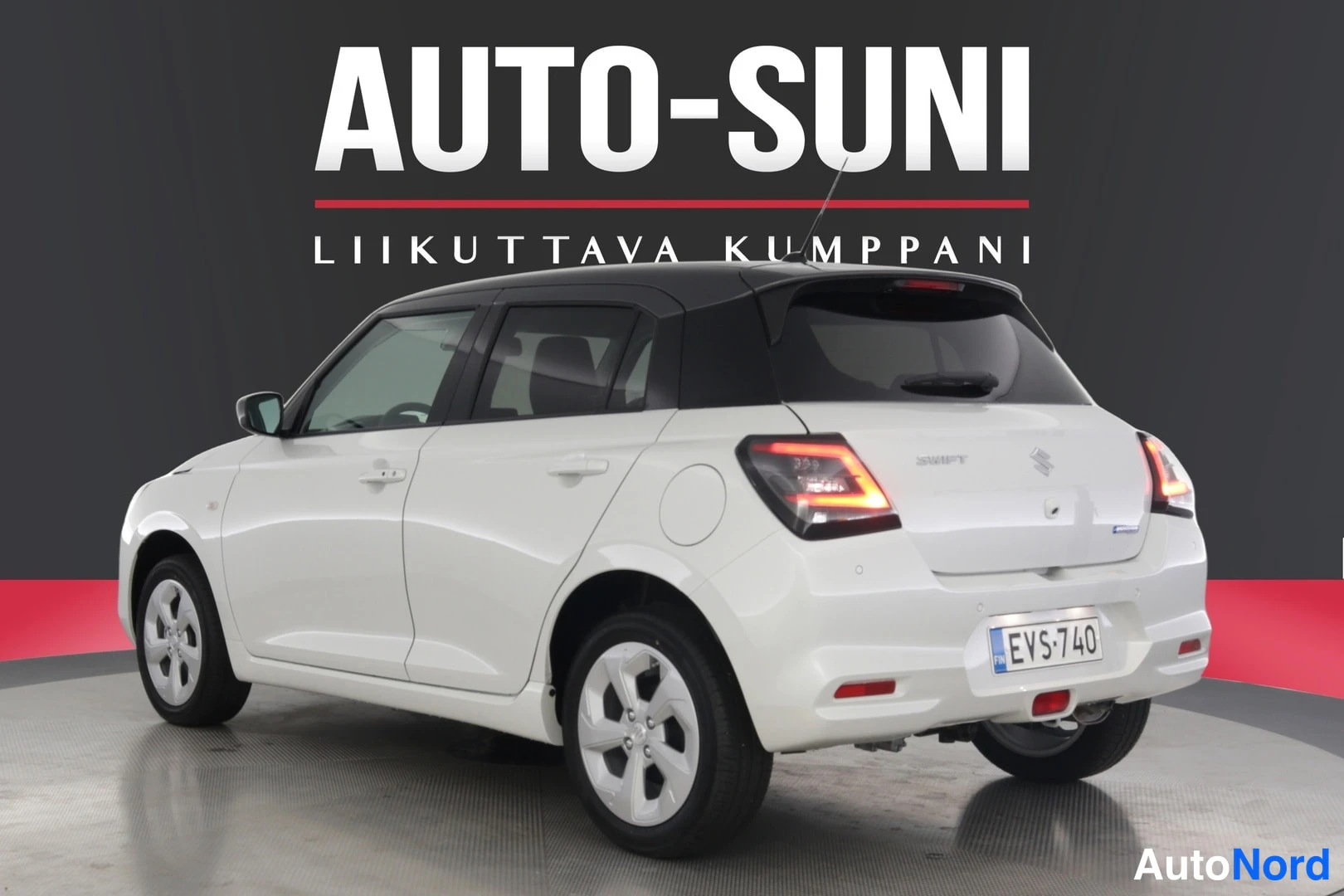 Takaviisto: Valkoinen Suzuki Swift takakolmannelta oikealta, rekisteritunnus, musta katto, takavalot palamassa.