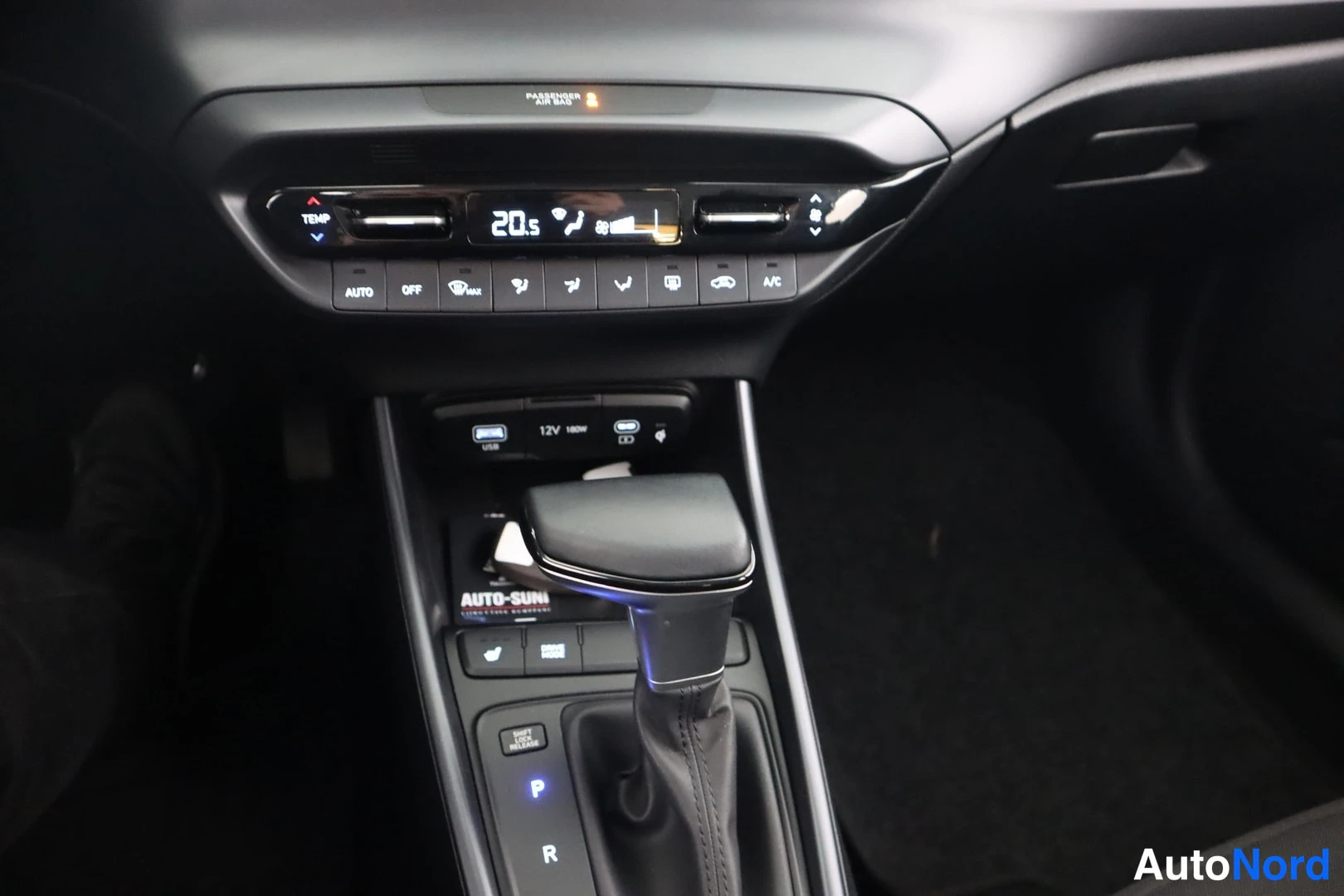 Edestä: Keskkonsoli lähikuvassa: ilmastointinäyttö 20,5 astetta, AUTO- ja A/C-napit, USB- ja 12V-liittimet sekä automaattivaihteen valitsin.
