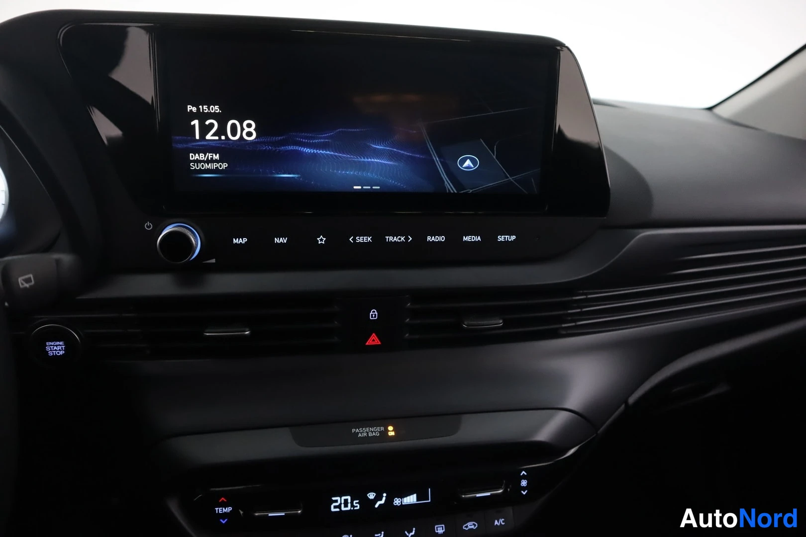 Edestä: Auton infotainment-näyttö: kello 12.08, pe 15.5., DAB/FM SuomiPop, MAP- ja NAV-napit sekä alla ilmastointipaneeli 20,5 astetta.
