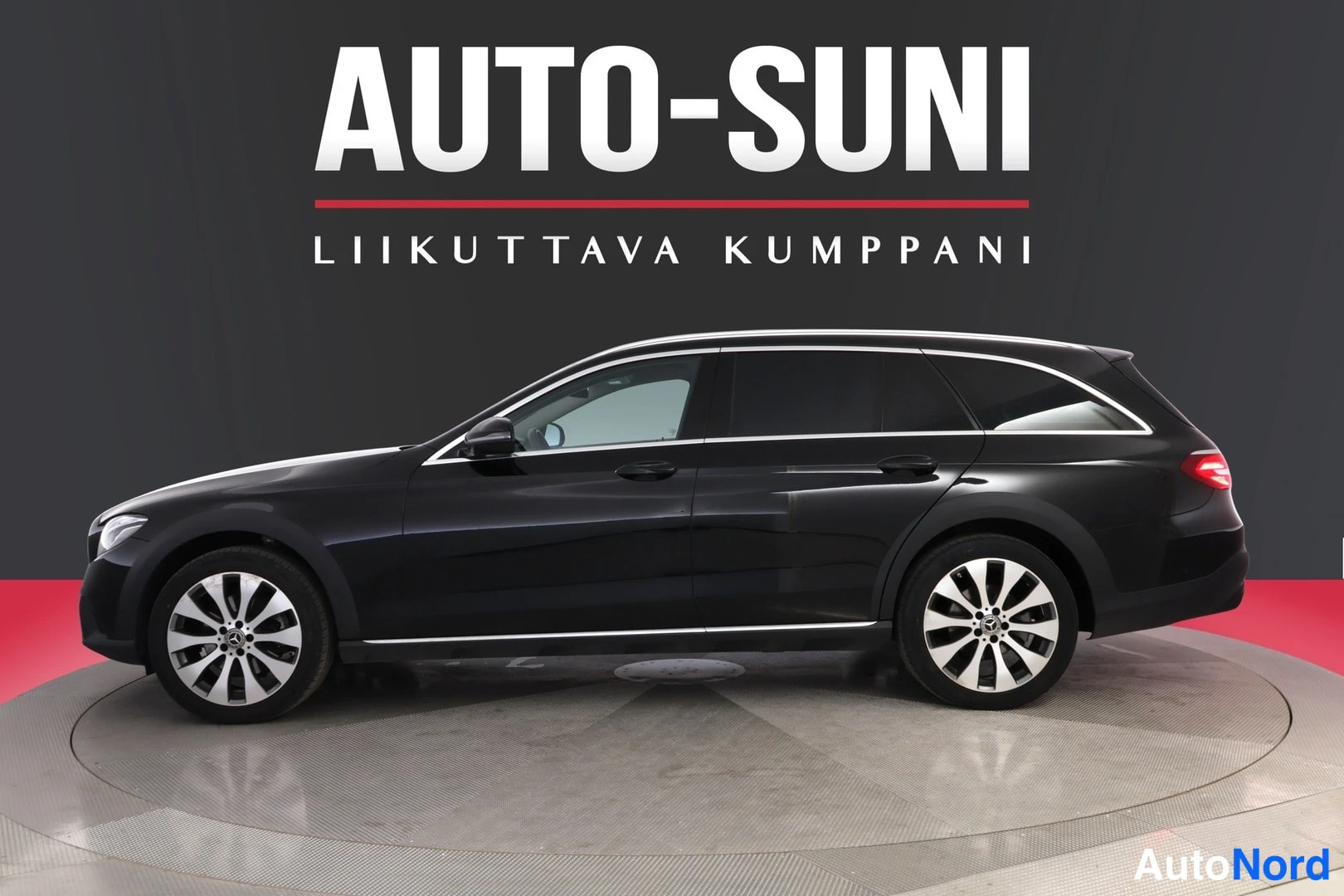 Etuviisto, nokka oikealle: Mercedes-Benz E -farmari sivulta etuviistosta, tumma koriväri, hopeiset kevytmetallivanteet.