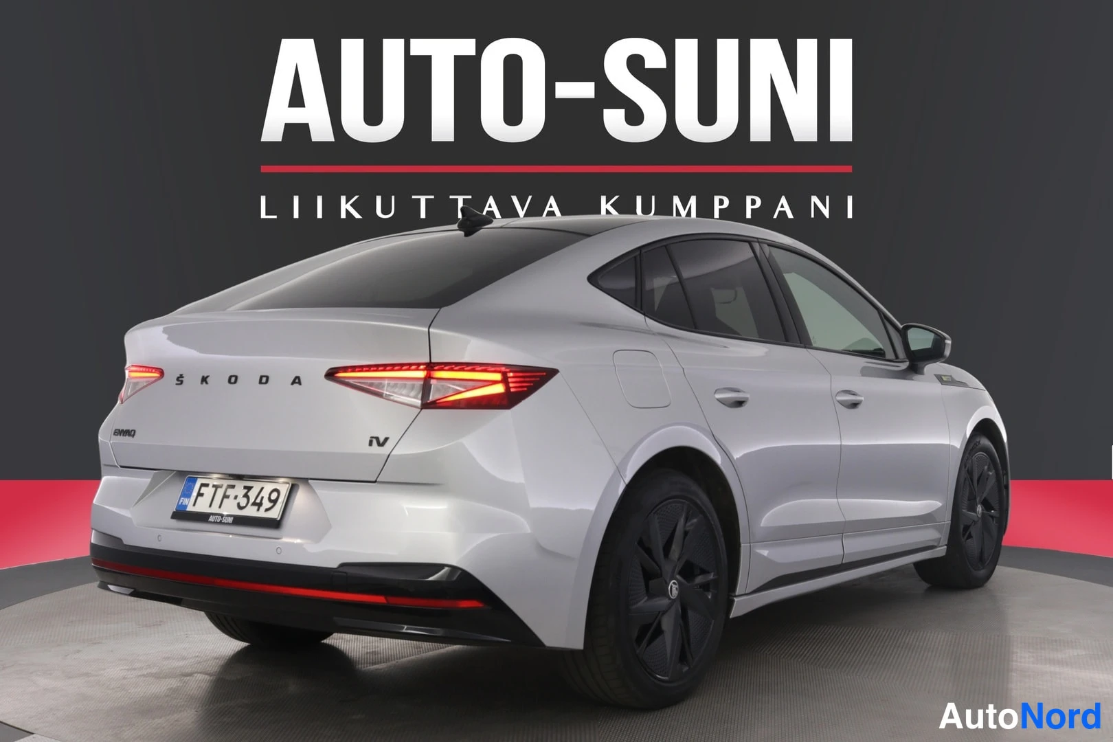 Takaviisto: Hopeanvärinen Skoda Enyaq takaviistosta oikealta; perässä ŠKODA- ja iV-tekstit, ENYAQ-merkintä, punaiset takavalot ja rekisterikilpi.