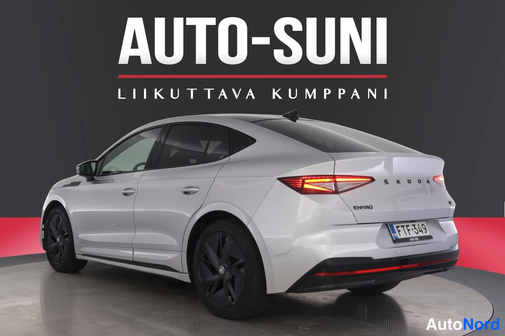 Takaviisto: Hopeanvärinen Skoda Enyaq takaviistosta vasemmalta; perässä ŠKODA- ja ENYAQ-tekstit, punaiset takavalot, rekisterikilpi ja musta diffuussori.