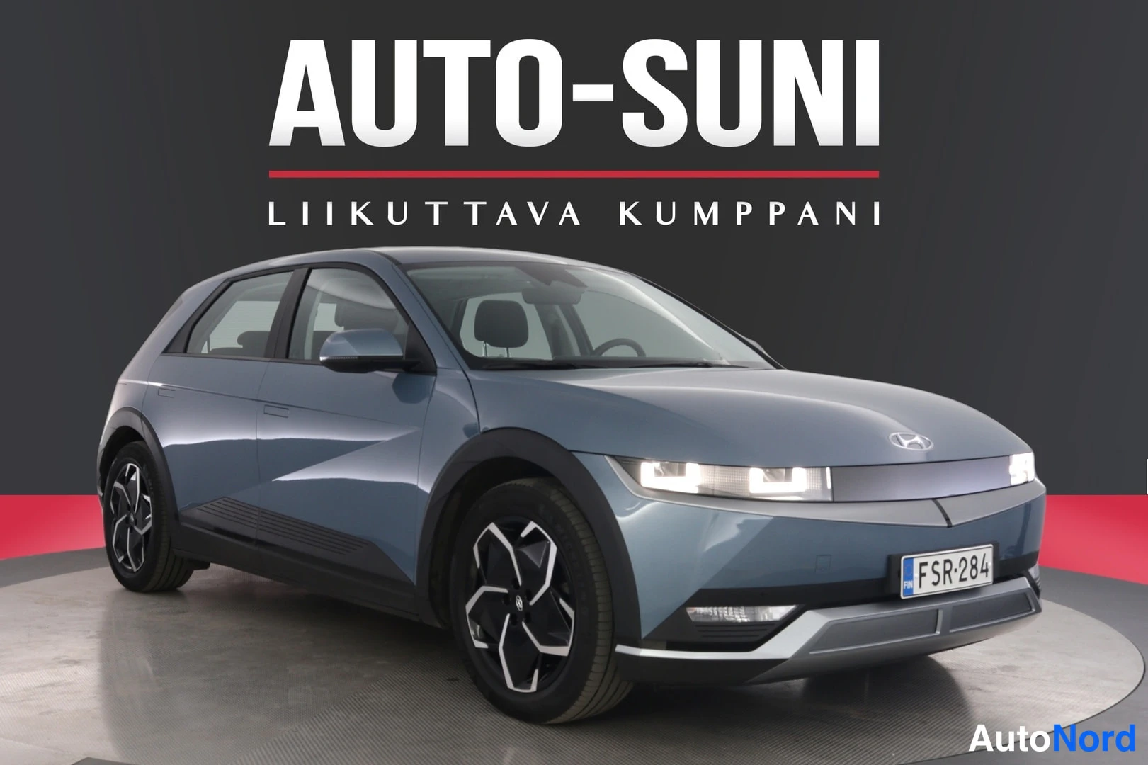 Etuviisto, nokka oikealle: Auton etukulma oikealta, harmaansininen Hyundai IONIQ 5 studiovalaistuksessa, rekisteritunnus.