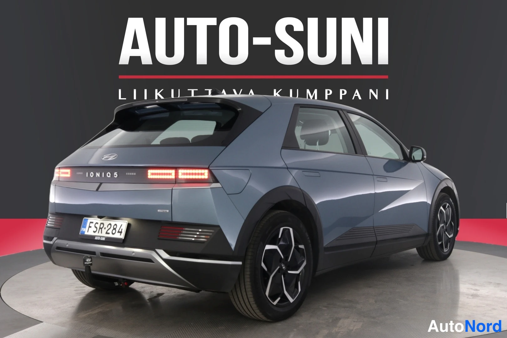 Takaviisto: Auton takakulma vasemmalta, harmaansininen Hyundai IONIQ 5, rekisteritunnus, takavalot IONIQ 5 -tekstillä.