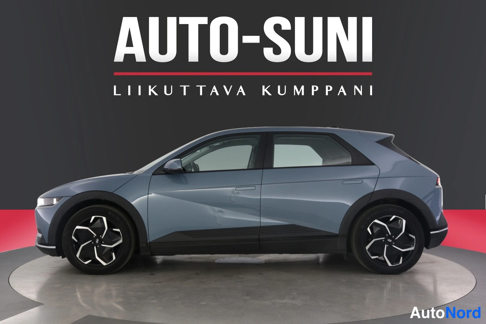Sivulta: Hyundai IONIQ 5:n sivuprofiili sinitharmaana studiotaustaa vasten, kummankin sivun pyörät ja ovenkahvat näkyvät.