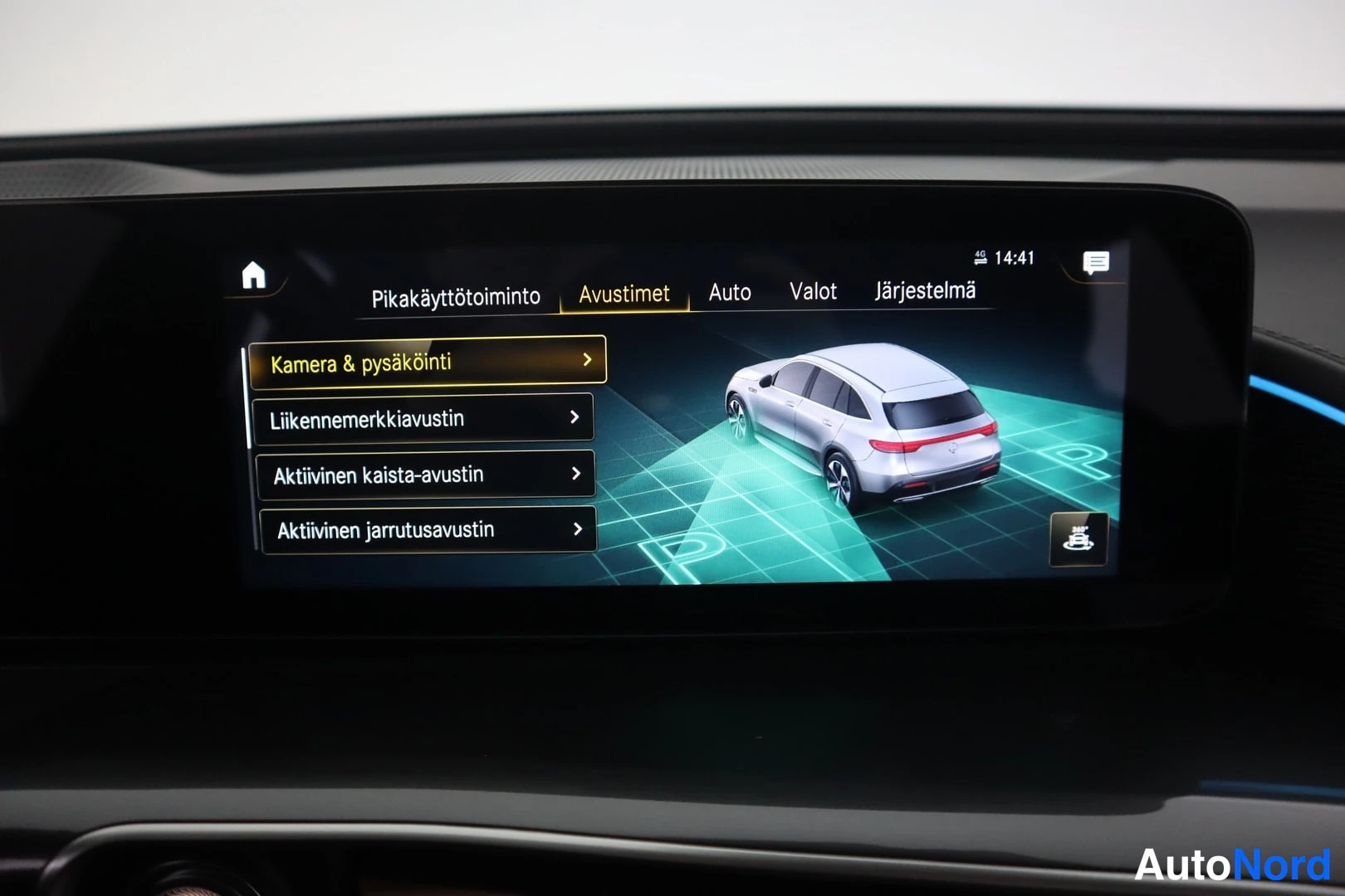 Yksityiskohta: Auton infotainment-näyttö, jossa Avustimet-valikko listaa kamera- ja pysäköinti-, liikennemerkki-, kaista- ja jarrutusavustimet sekä auton graafinen kuva.