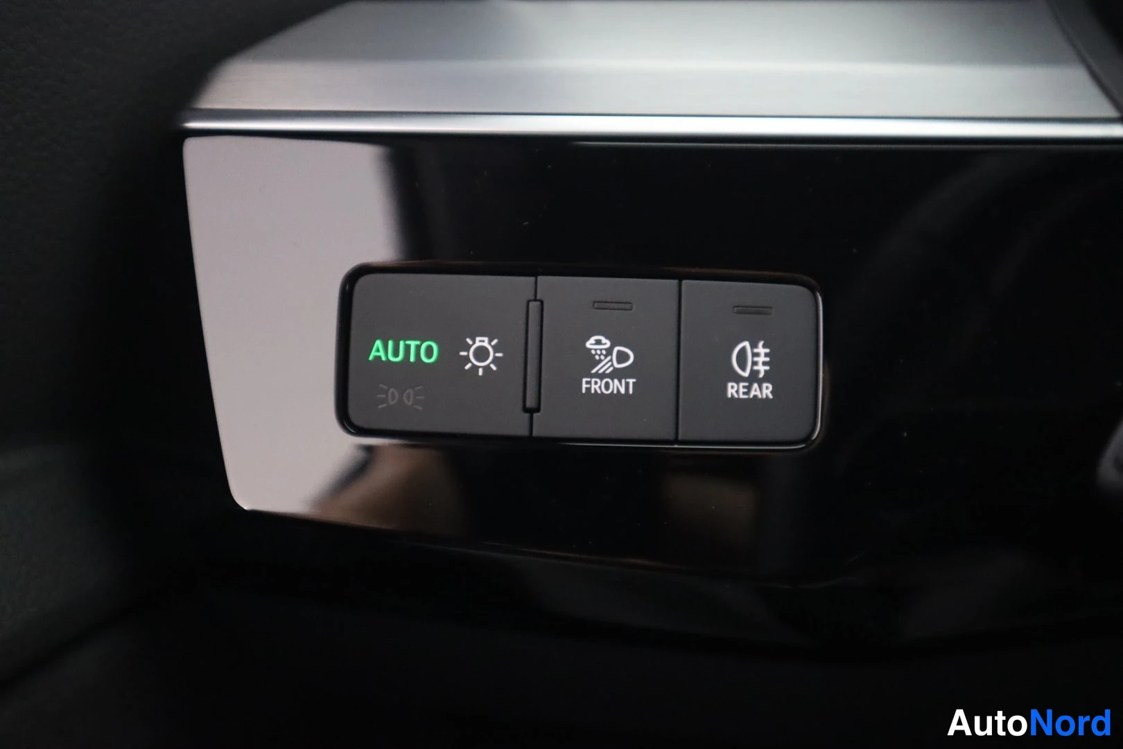 Muu: Sisätilan lähikuva valo- ja sumuvalokytkimistä: AUTO-näppäin vihreällä tekstillä, sekä FRONT- ja REAR-sumuvalon näppäimet.