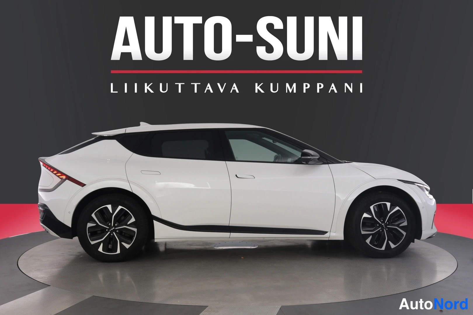 Sivulta: Kia EV6 sivulta kuvattuna, valkoinen crossover tummassa studiossa.