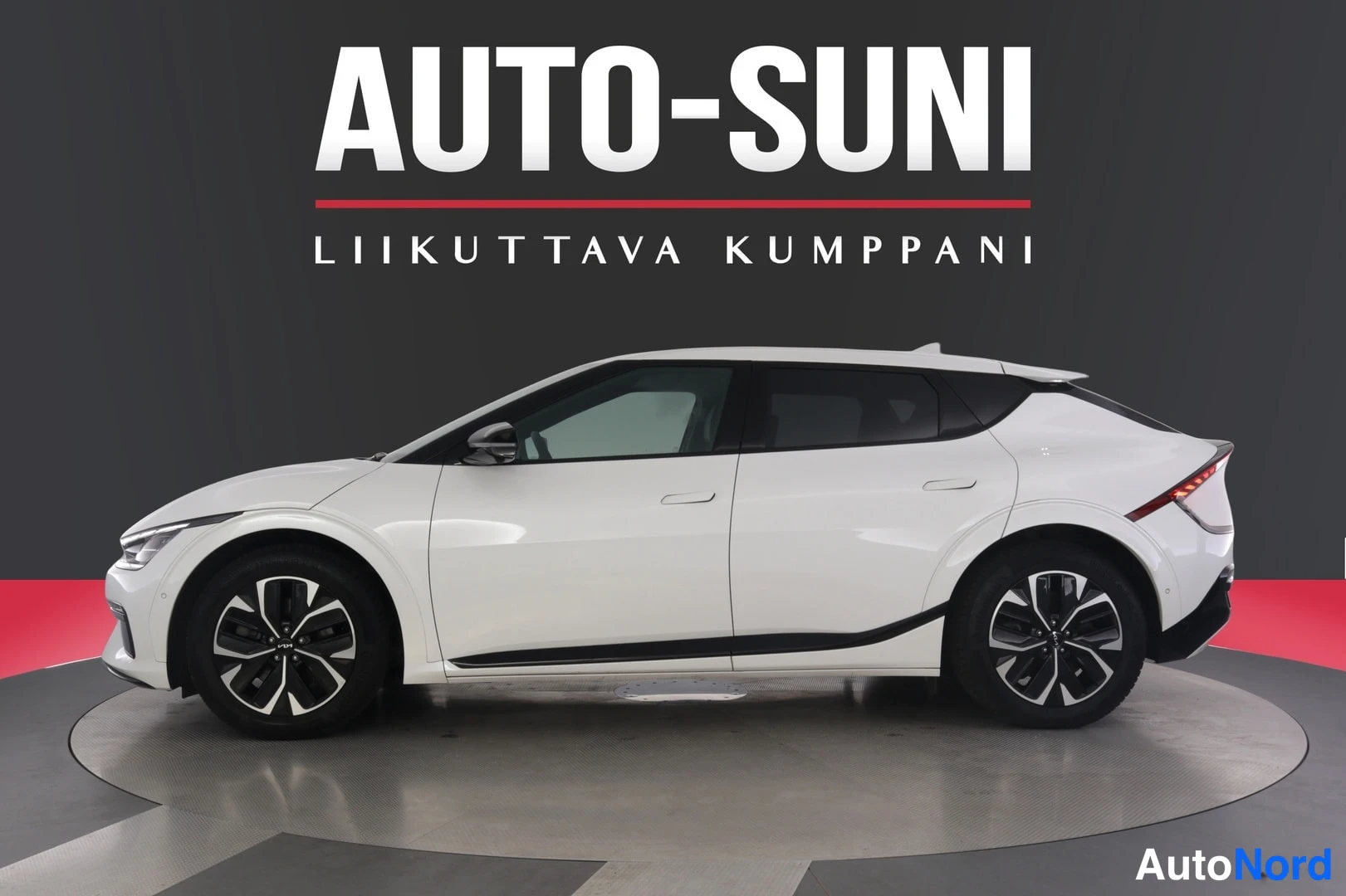 Sivulta: Valkoinen Kia EV6 sivulta profiilikuvattuna tummassa studiossa.