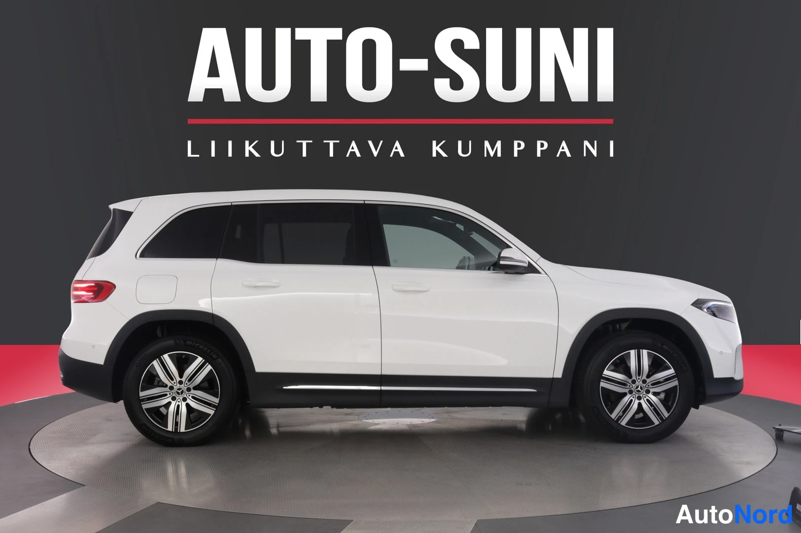 Sivulta: Valkoinen Mercedes-Benz EQB -SUV sivuprofiilikuvassa studio­taustaa vasten.