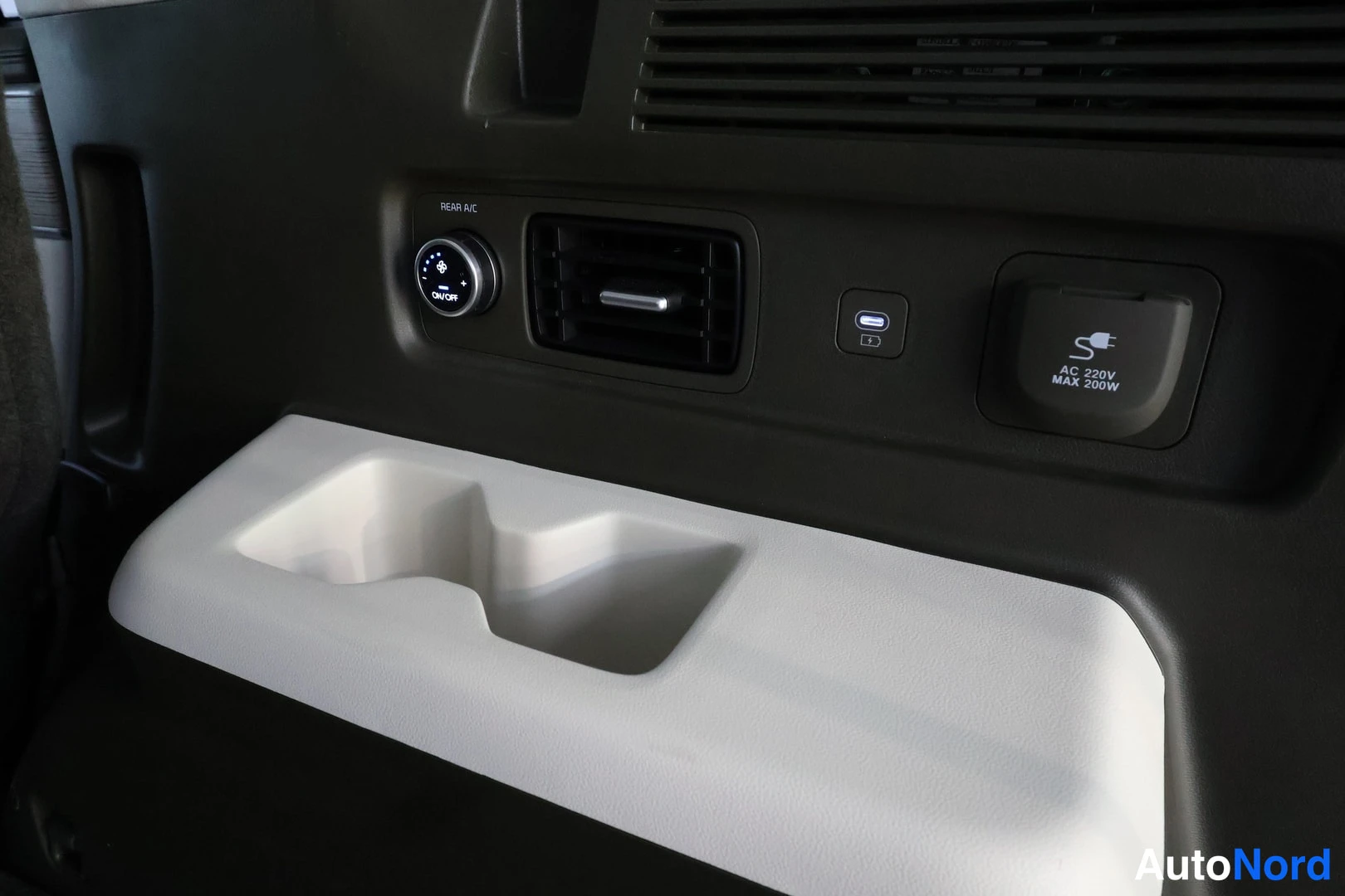 Muu: Sisätilakuvassa takaosan ilmastointilohko: REAR AC -säädin, ilmanvetoaukko, USB-C-portti ja AC 220V MAX 200W -pistorasian kansi.