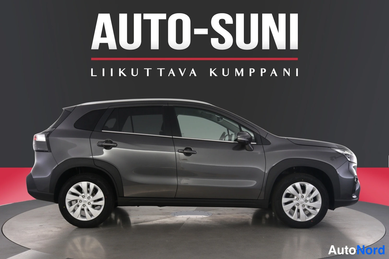 Sivulta: Auton sivunakymä vasemmalta: harmaan crossovin kylki, 16 tuuman pyörät ja kattopalkit näkyvät.