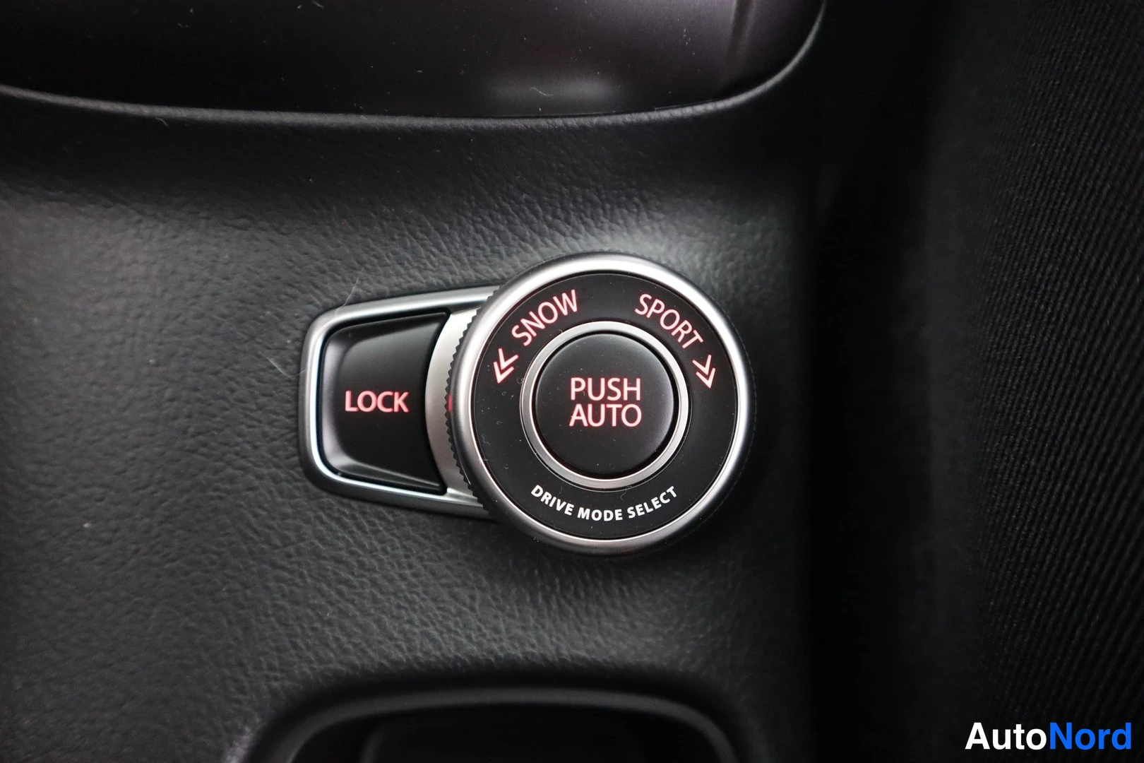 Muu: Ajovalintakytkin, jossa vaihtoehdot LOCK, SNOW ja SPORT, keskellä PUSH AUTO ja teksti DRIVE MODE SELECT