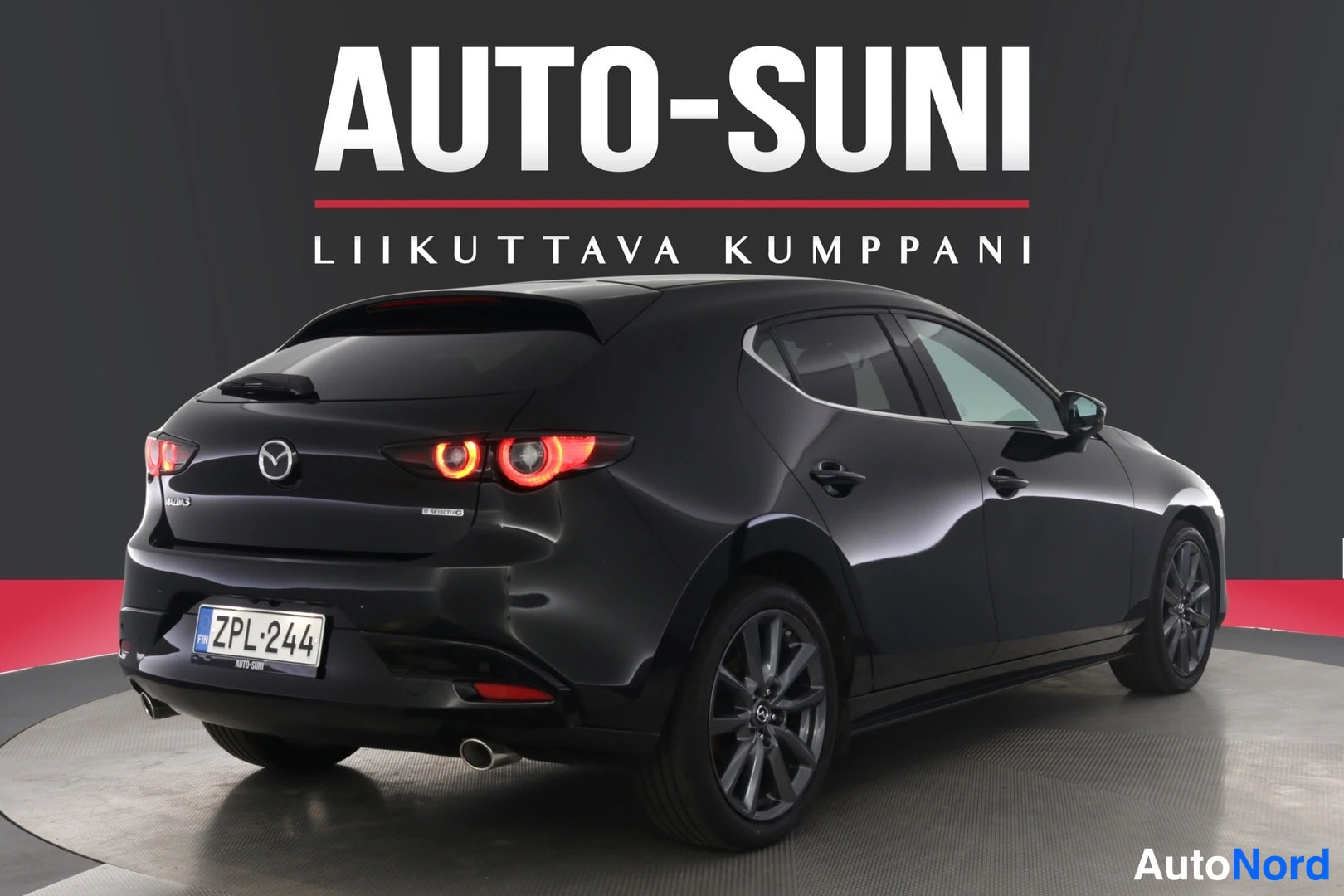 Takaviisto: Musta Mazda 3 viistosti takaa, syttyneet takavalot, rekisteri.