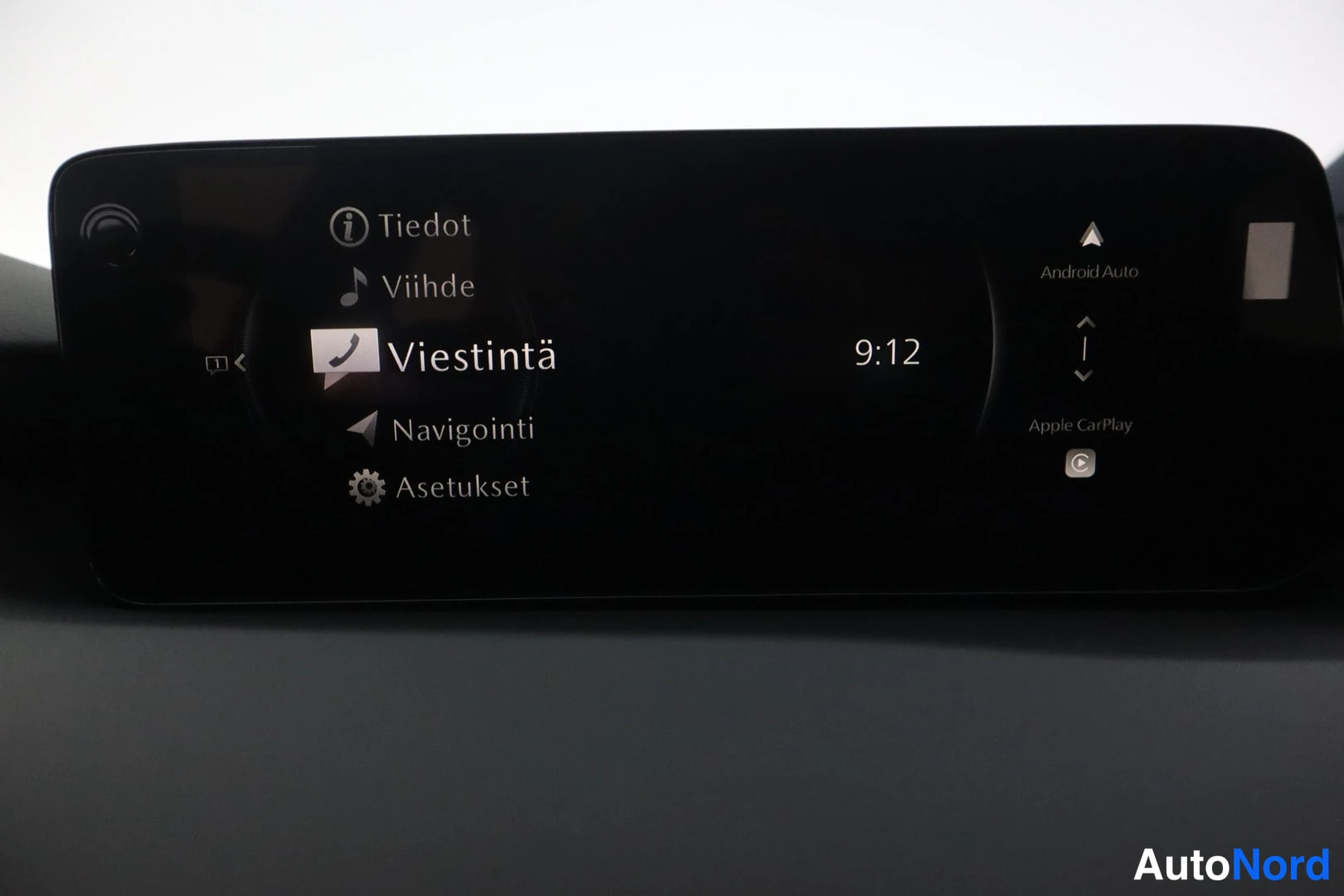 Yksityiskohta: Ajoneuvon keskinäytön valikko, jossa valittuna kohta Viestintä; näkyvillä myös Tiedot, Viihde, Navigointi ja Asetukset sekä Android Auto- ja Apple CarPlay-symbo