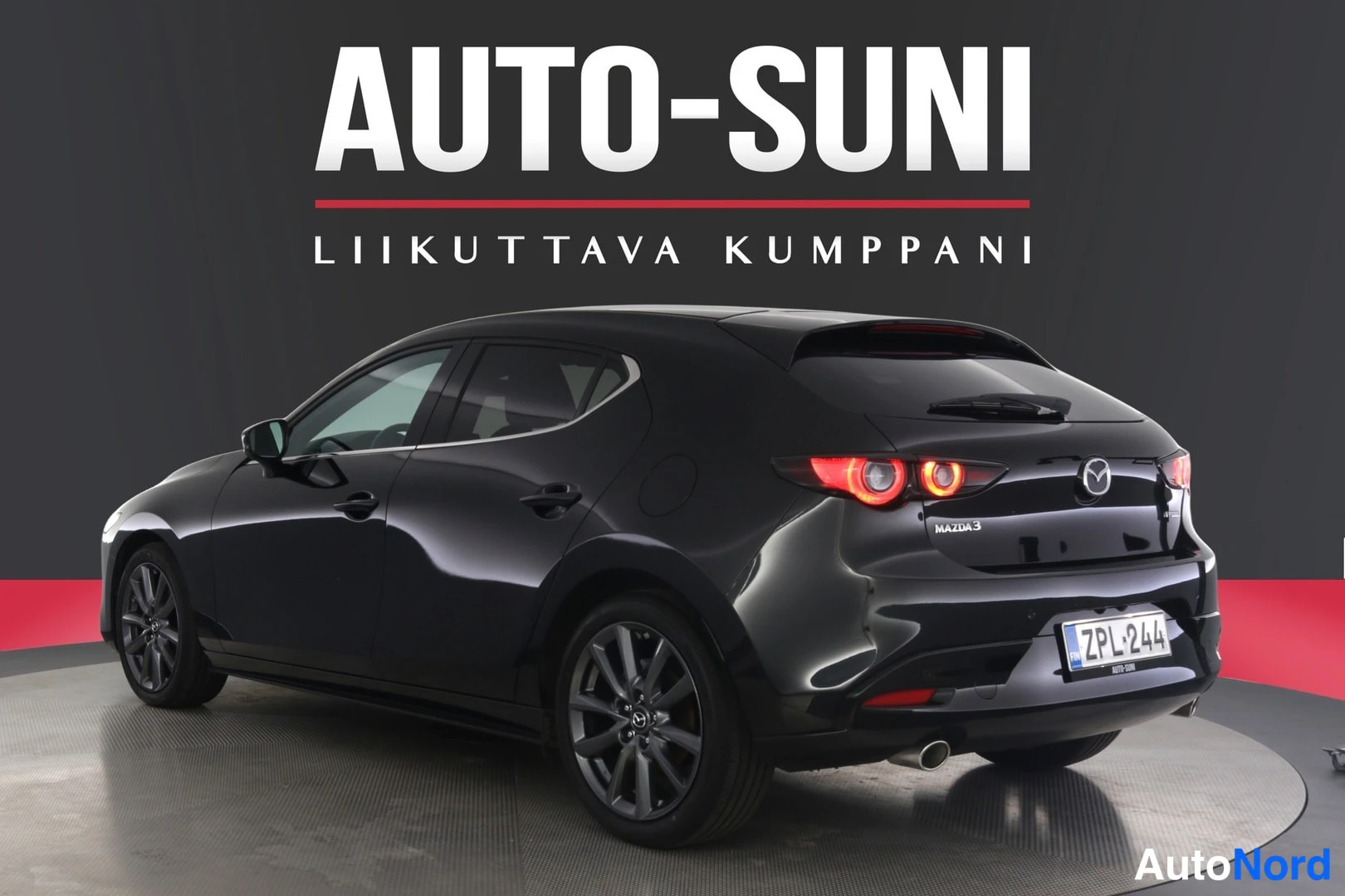 Takaviisto: Musta Mazda 3 viistosti takaa vasemmalta, pyörivällä alustalla, rekisteri.