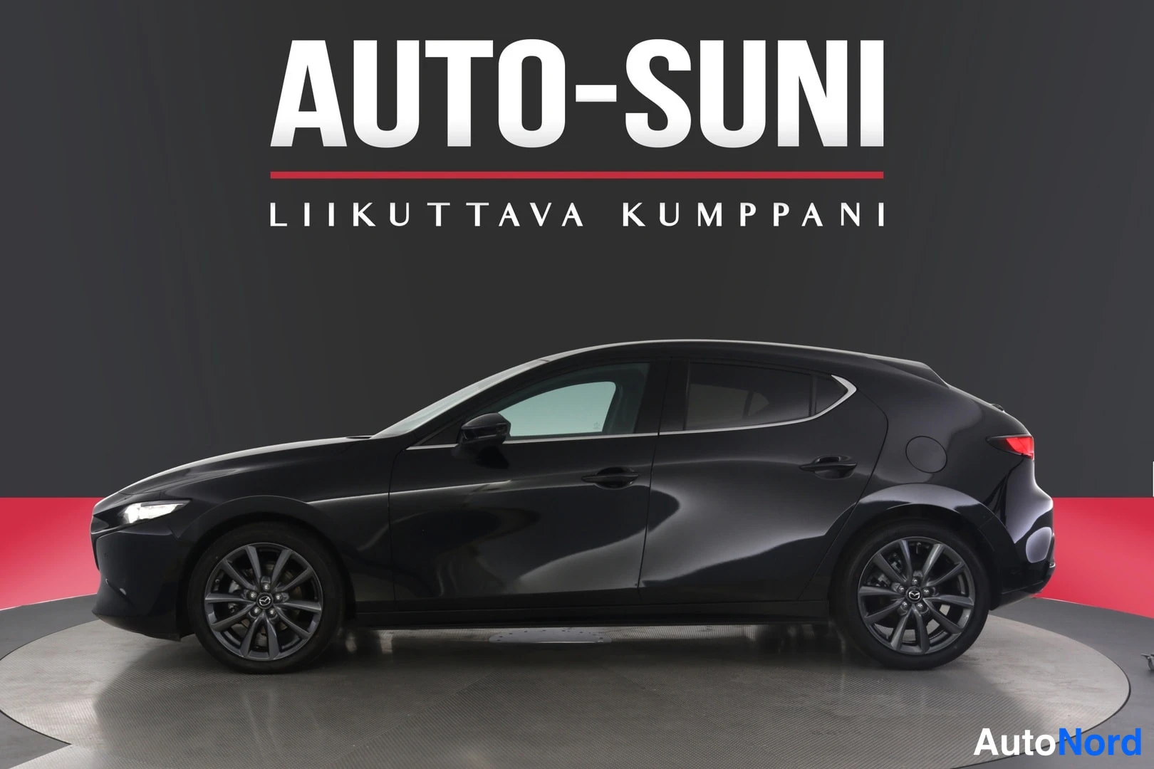 Sivulta: Mazda 3 -henkilöauton sivuprofiili tummassa studioympäristössä