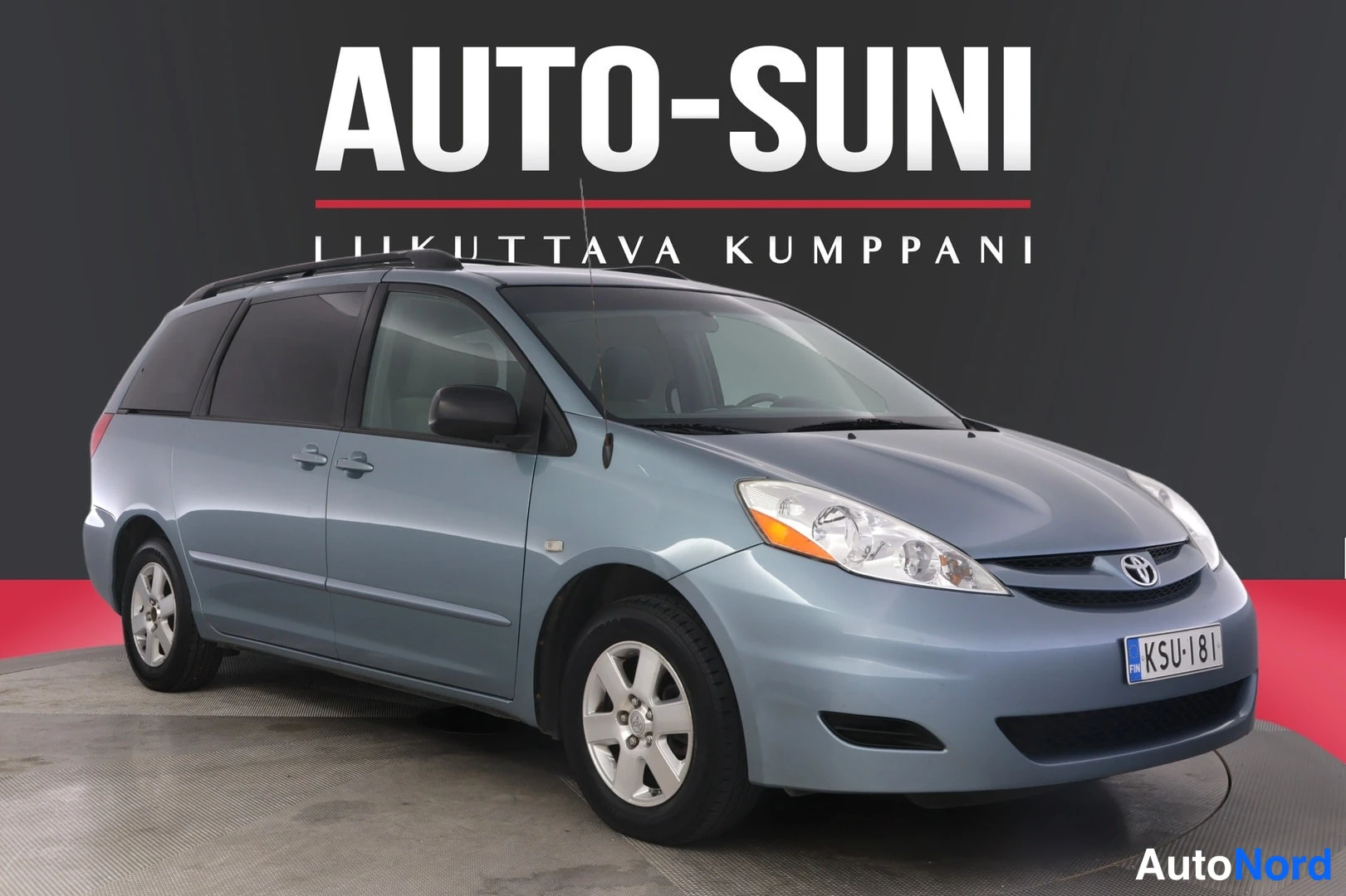 Etuviisto, nokka oikealle: Sinertävänharmaa Toyota Sienna -pakuriauto etukulmasta, kattosearch kate ja etulokasuoja näkyvät.