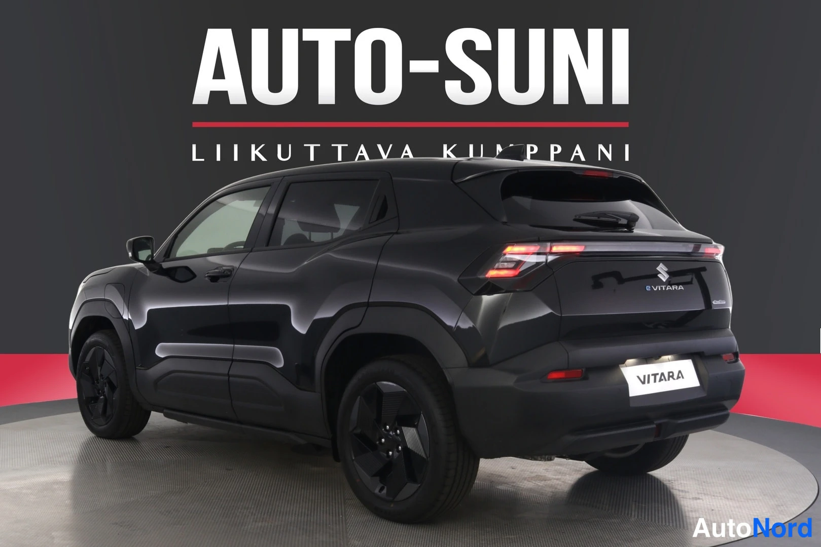 Takaviisto: Mustan Suzuki Vitaran takakulma vasemmalta, takavaloja ja VITARA-tunnusta näkyen, Auto-Sunin taustalla.