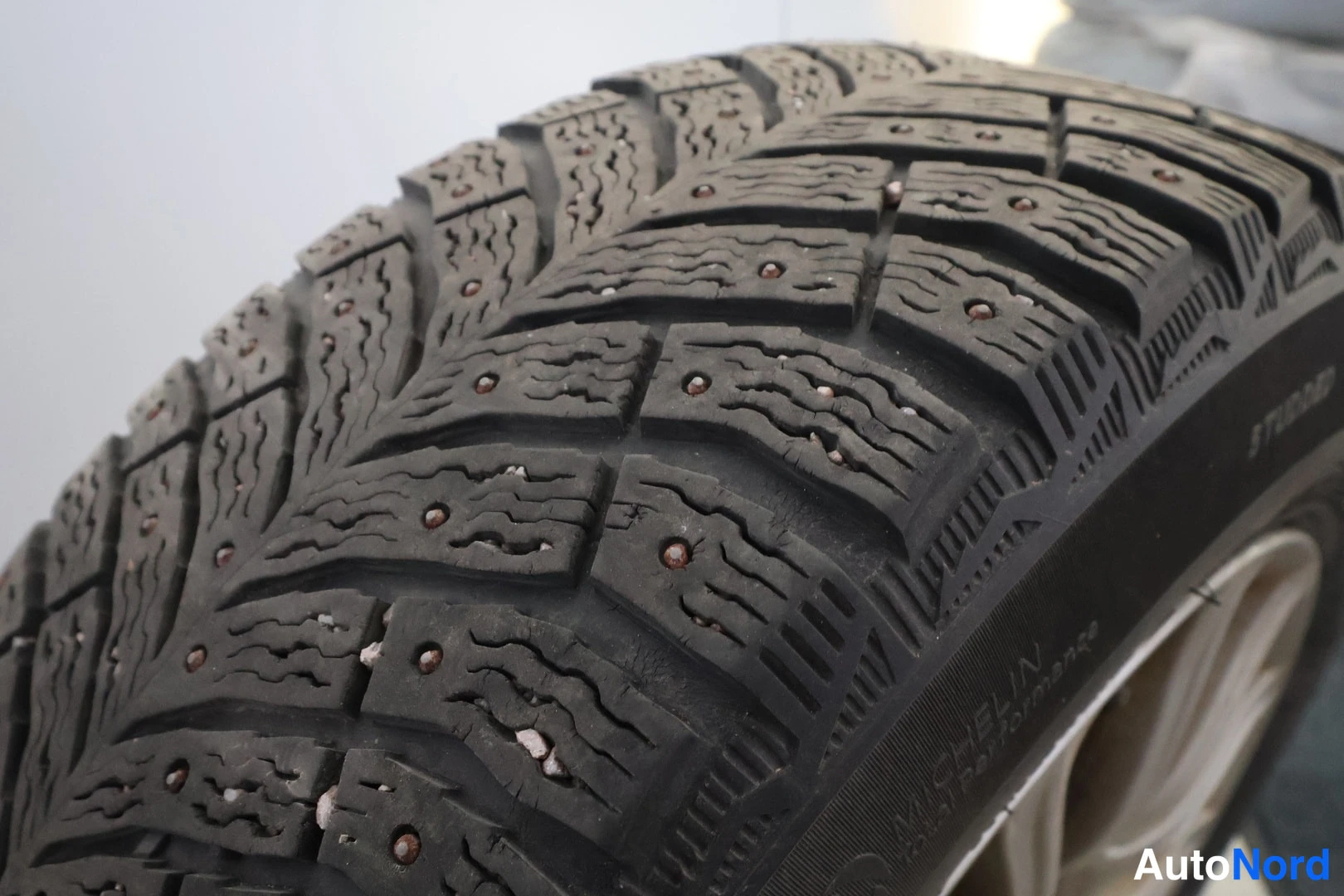 Yksityiskohta: Nastarenkaan kulutuspinnan lähikuva, pultit ja MICHELIN-merkintä näkyvät.