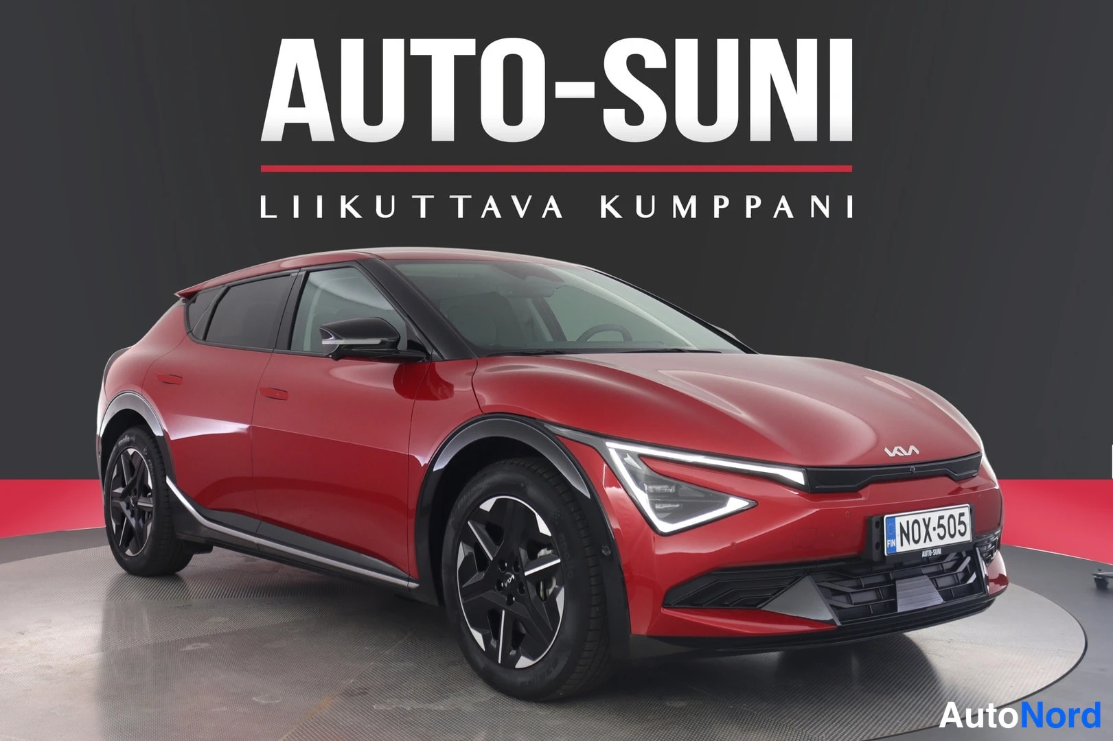 Etuviisto, nokka oikealle: Punainen Kia EV6 etuosa kolmivartaloasennossa oikealta nähtynä, rekisterikilpi.