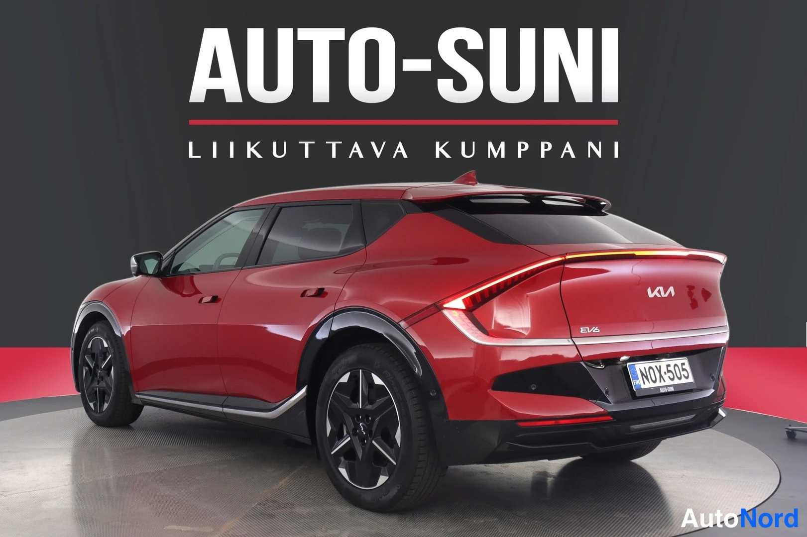 Takaviisto: Punainen Kia EV6 takaosa kolmivartaloasennossa vasemmalta nähtynä, perävasa, EV6-merkintä perällä.
