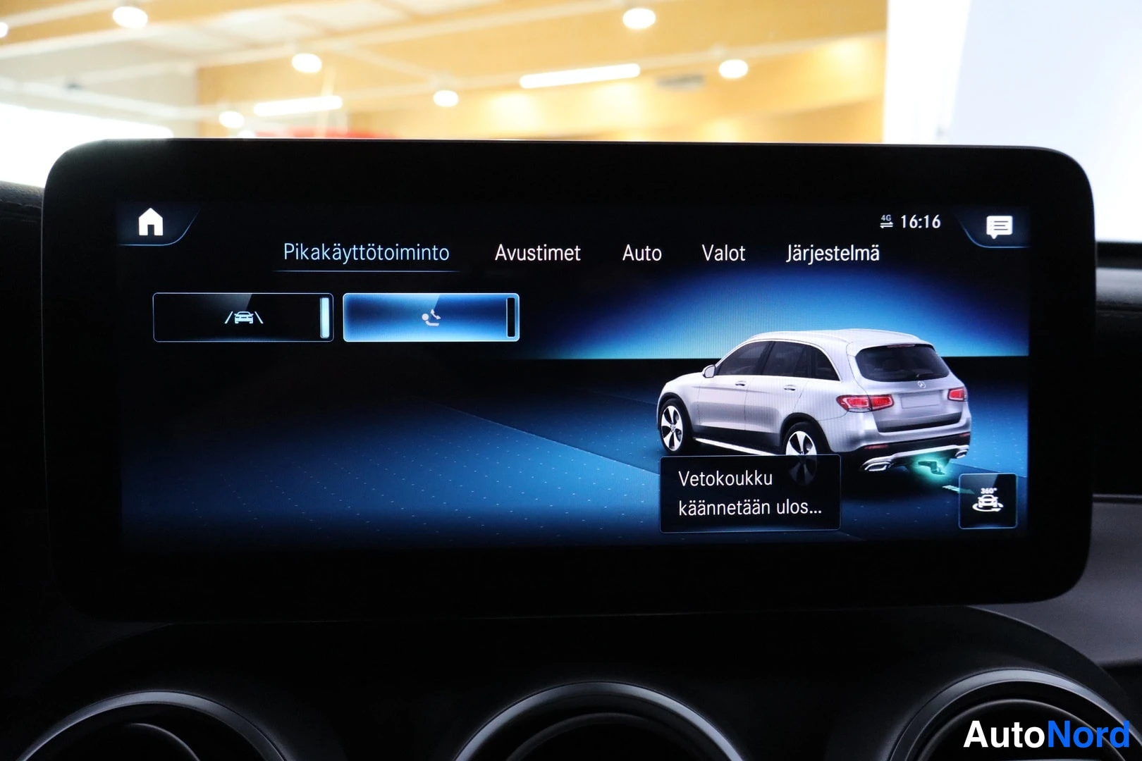 Muu: Ajoneuvon infotainment-näyttö, jossa valikot Pikakäyttötoiminto, Avustimet, Auto, Valot ja Järjestelmä; kuvassa ajoneuvon kuva ja teksti 'Vetokoukku käännetään