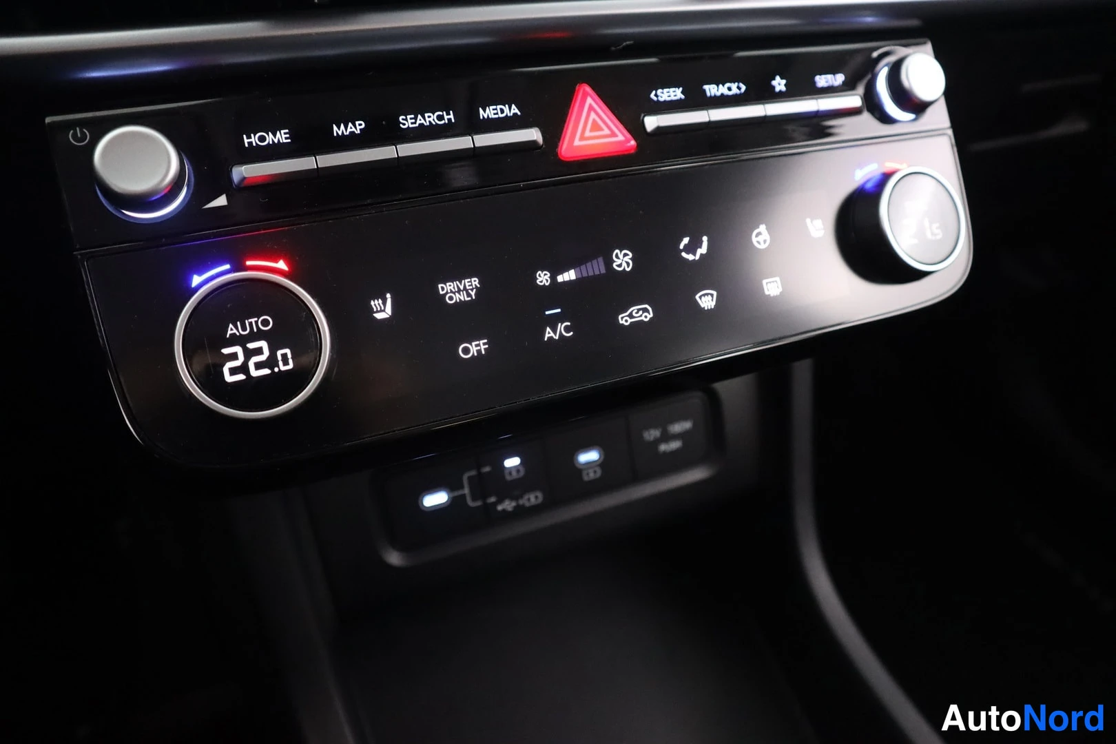 Etuviisto, nokka vasemmalle: Auton automaattisen ilmastoinnin ja median hallintapaneeli: lämpötila 22.0, AUTO, A/C, OFF, DRIVER ONLY sekä napit HOME, MAP, SEARCH ja MEDIA; varoitus
