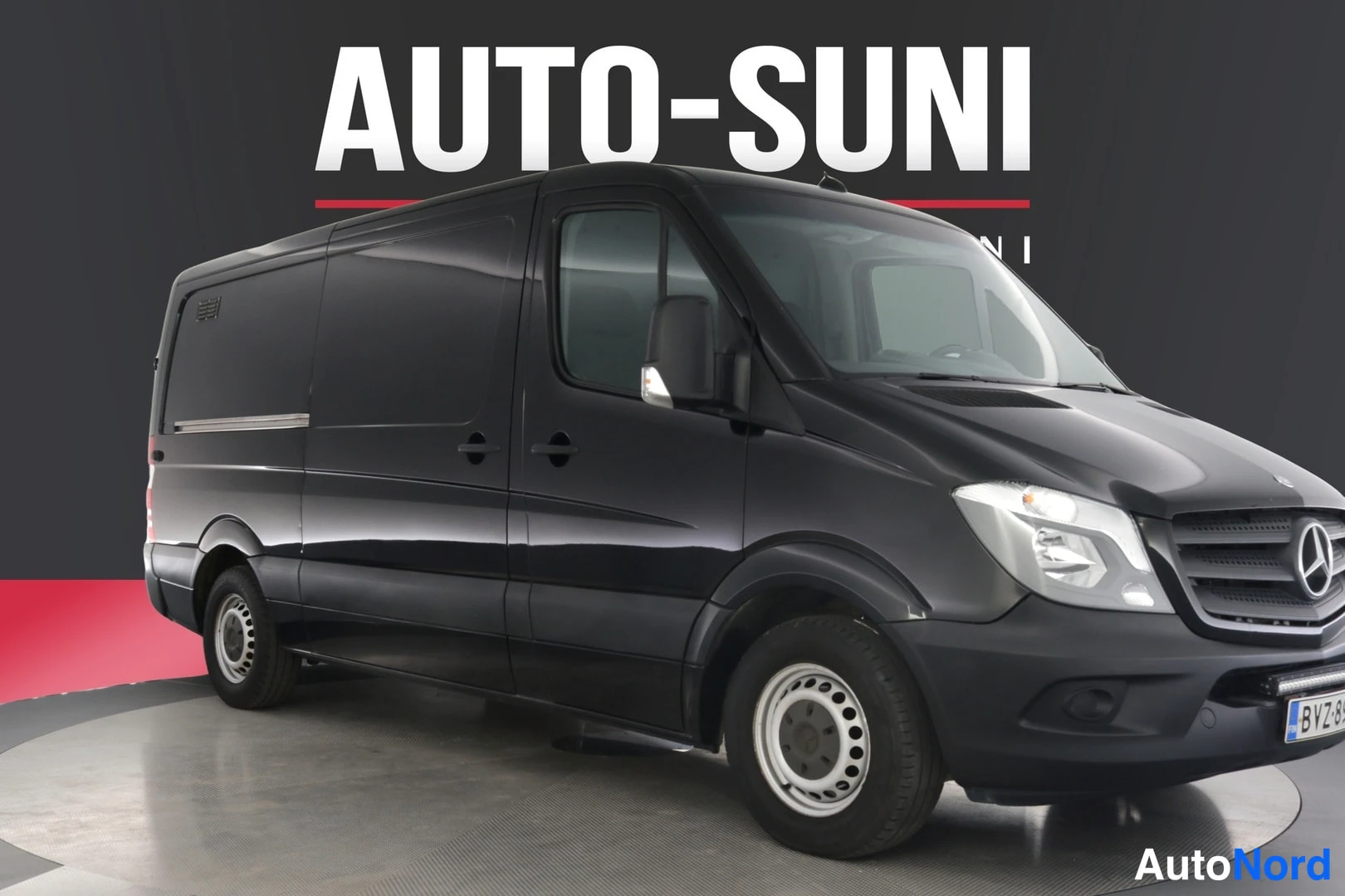 Etuviisto, nokka oikealle: Musta Mercedes-Benz Sprinter -pakettiauto etuviistöstä oikealta kuvattuna studiossa.