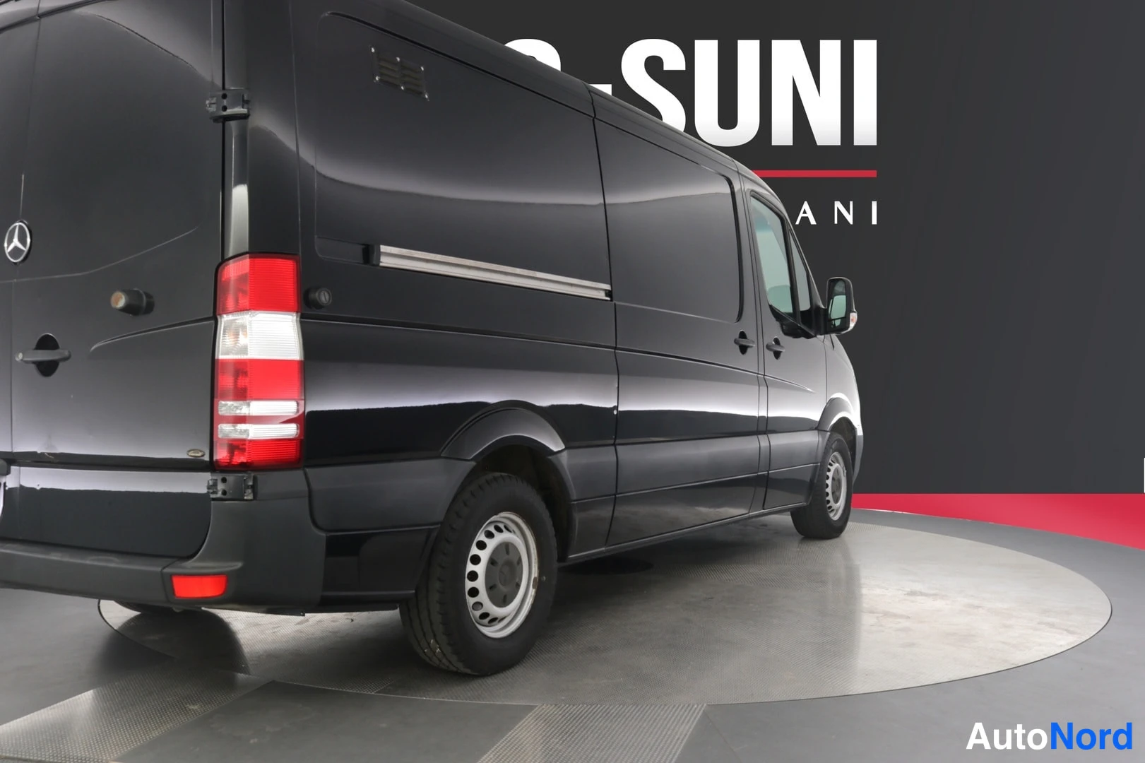 Takaviisto: Mustan Mercedes-Benz Sprinter -pakettiauton takaviistö vasemmalta kuvattuna studiossa.