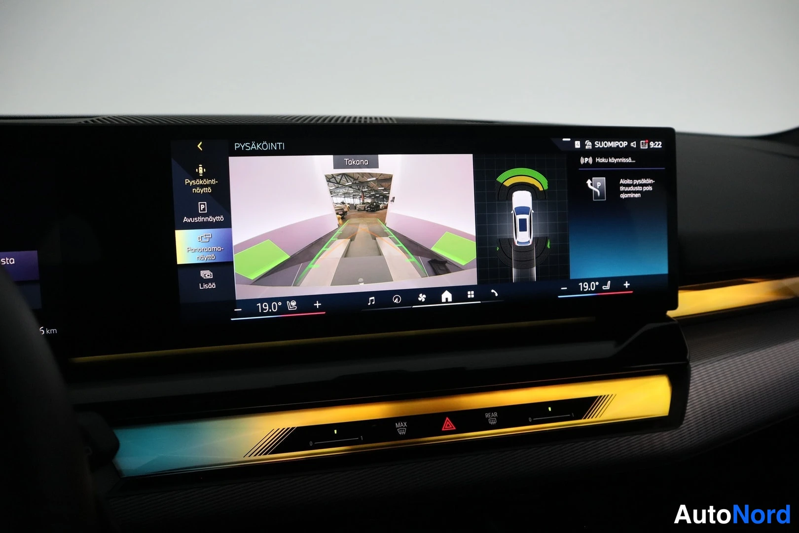 Muu: Takana näkyvä infotainment-näyttö, jossa pysäköintikamera-näkymä, pysäköintiavustajan grafiikka ja suomenkielisiä valikkoja kuten 'PYSÄKÖINTI' ja 'Pysäköinti-nä